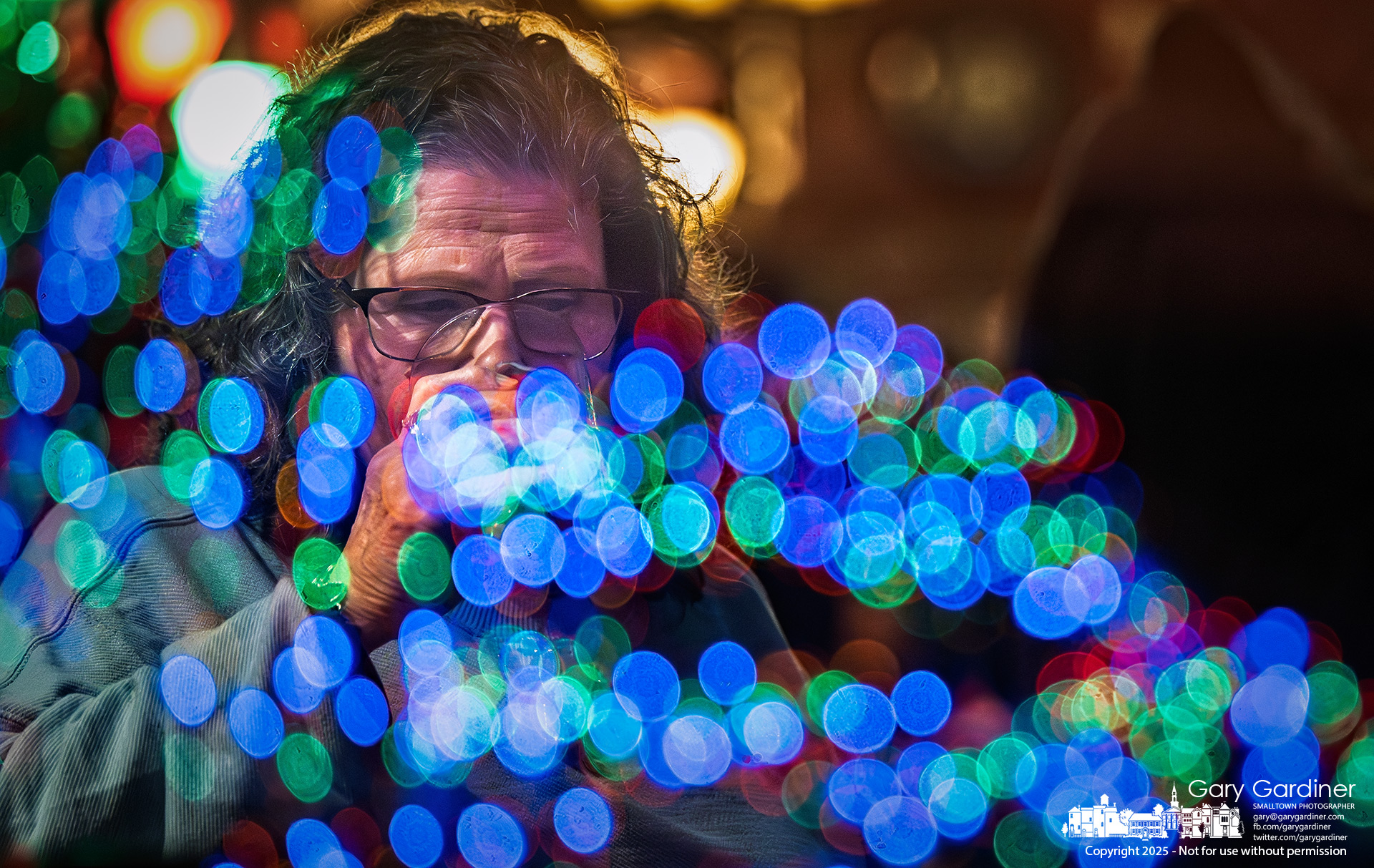 A woman enjoys a drink in the front window of Old Bag o’ Nails as colorful reflections from a decorated Electric Division truck light up the glass during the town’s pre-Christmas tree lighting festivities. My Final Photo for December 5, 2025.
