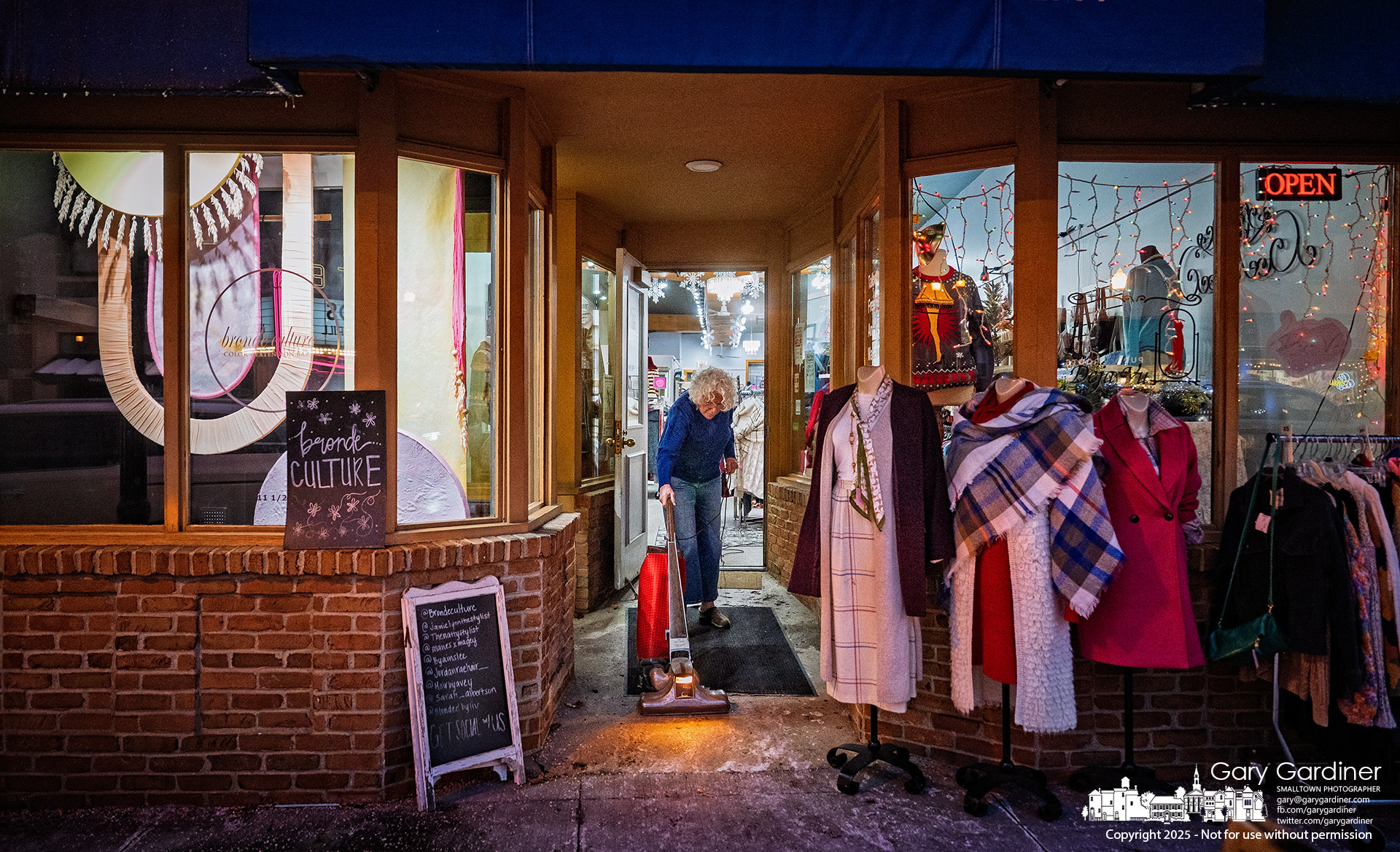 A worker cleans the doorway rug at Deja Vu, a women’s clothing consignment shop in Uptown Westerville, at closing time after snow tracked in during the day melted. My Final Photo for December 16, 2025.