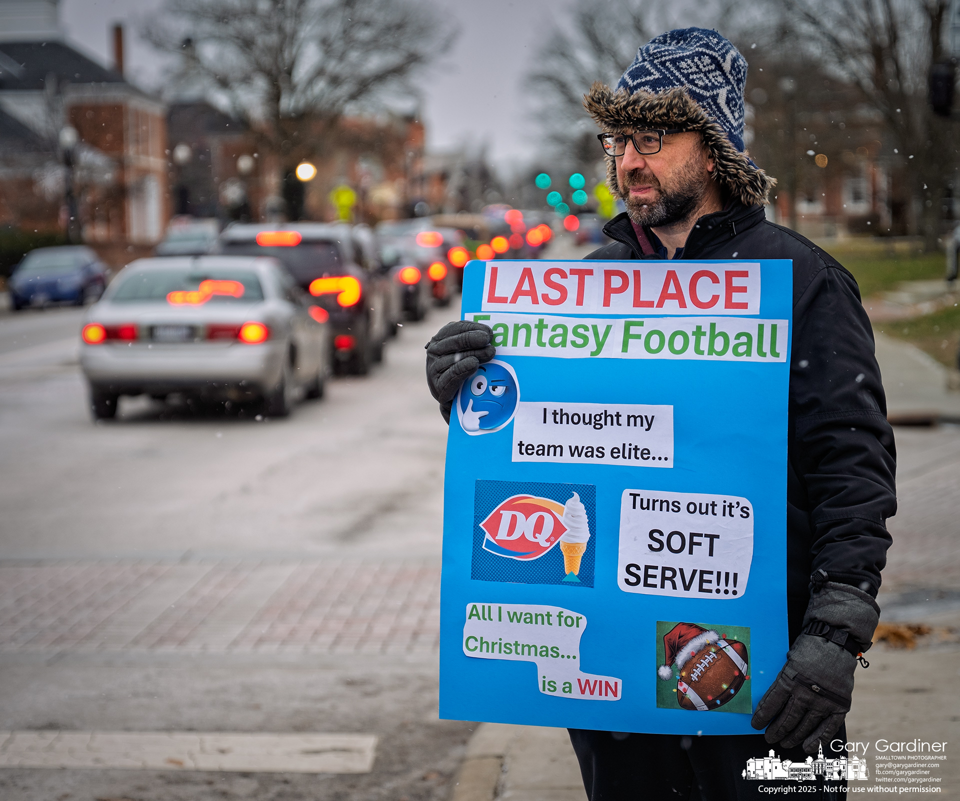Josh Rohr, who finished last in his Fantasy Football league standings, stands in the cold and snow on Friday in front of the Dairy Queen on State Street as punishment for his poor finish. My Final Photo for December 19, 2025.