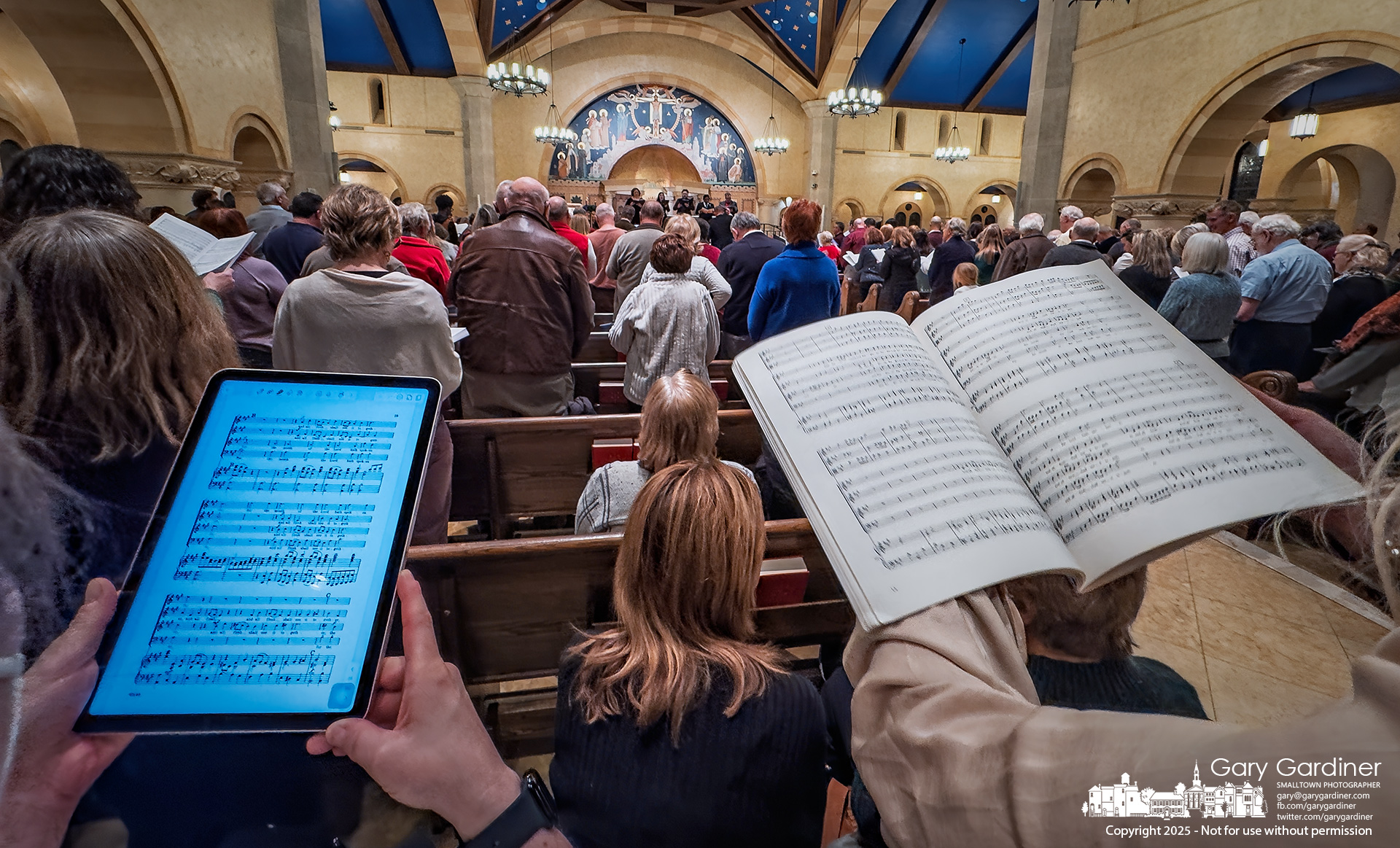 Two women, one with an iPad and the other with a printed score, join the sing-along of Handel’s Messiah performed Sunday night at St. Paul the Apostle Catholic Church by the Westerville Symphony. My Final Photo for December 7, 2025.