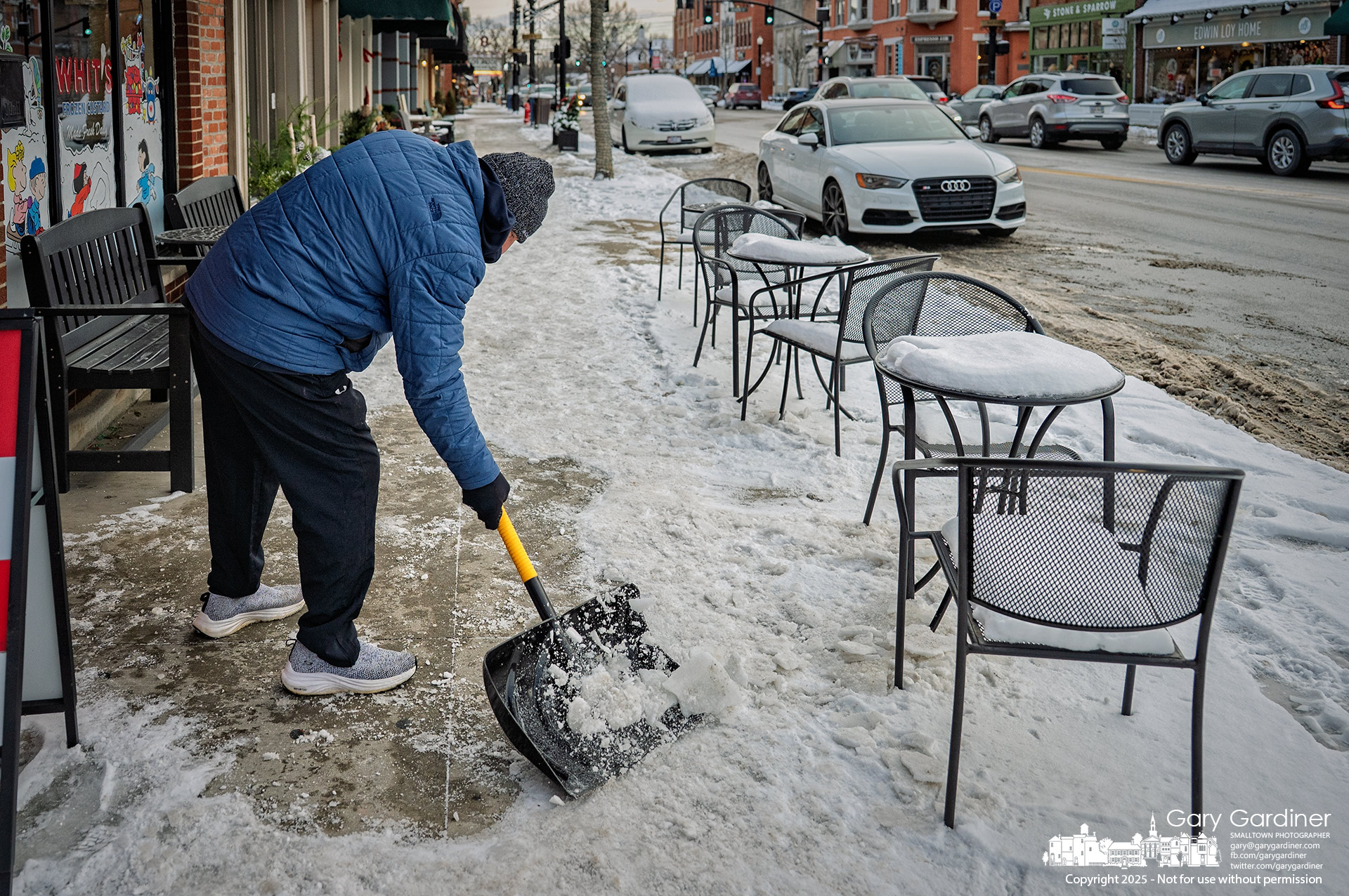 Whit's Frozen Custard owner Joe Schirtzinger shovels snow and ice from the sidewalk outside his Uptown Westerville shop. My Final Photo for December 15, 2025.
