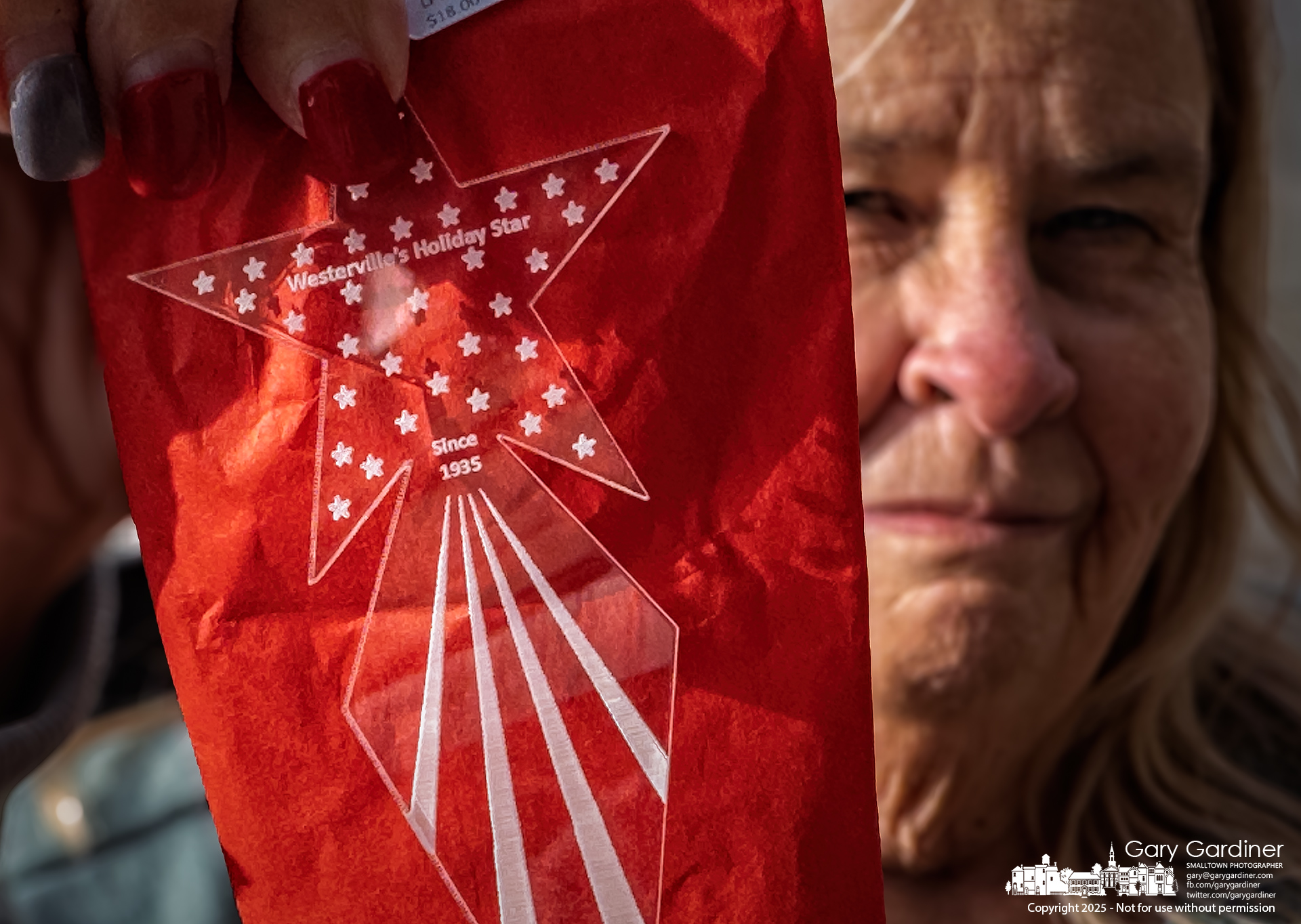 Cathy Noskowiak shows one of the seven Westerville Holiday Stars she bought on Christmas Eve as gifts for her family and friends, recalling a childhood memory: “I knew it was Christmas when the star was hung right there,” she said, pointing to State and Main in Uptown Westerville. My final Photo for December 24, 2025.