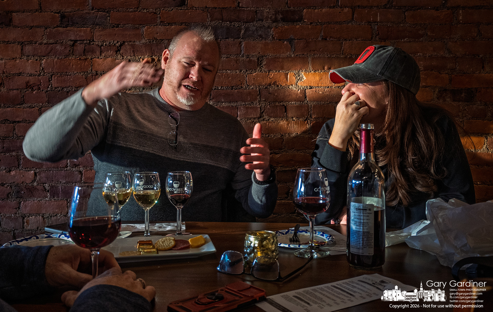 Friends enjoy conversation, wine, and a stream of warm sunset light streaming across their table at Good Vibes in Uptown. My Final Photo for January 22, 2026.