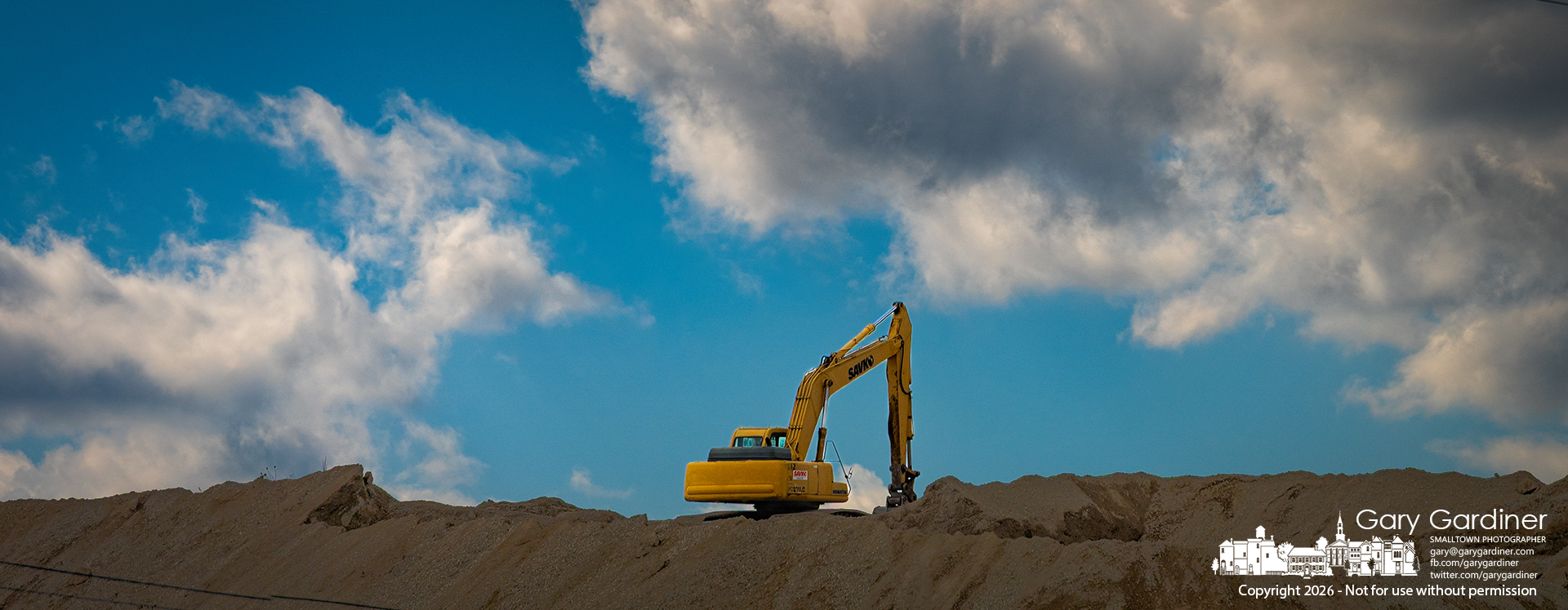 An idle backhoe sits atop a small mountain of gravel destined to be processed into concrete at a plant along Westerville Road. (My Final Photo for February 20, 2026)