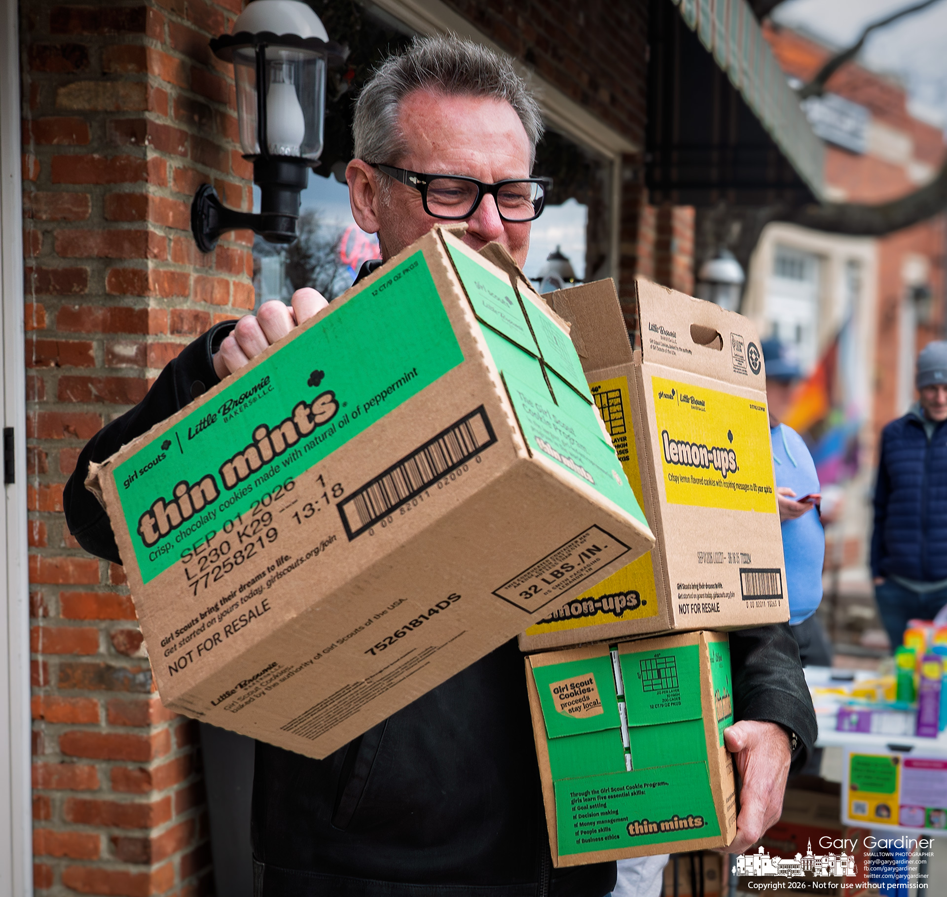 A well-stocked Girl Scout cookie customer walks away with 27 boxes of cookies from in front of Java Central Saturday afternoon. (My Final Photo for February 21, 2026)