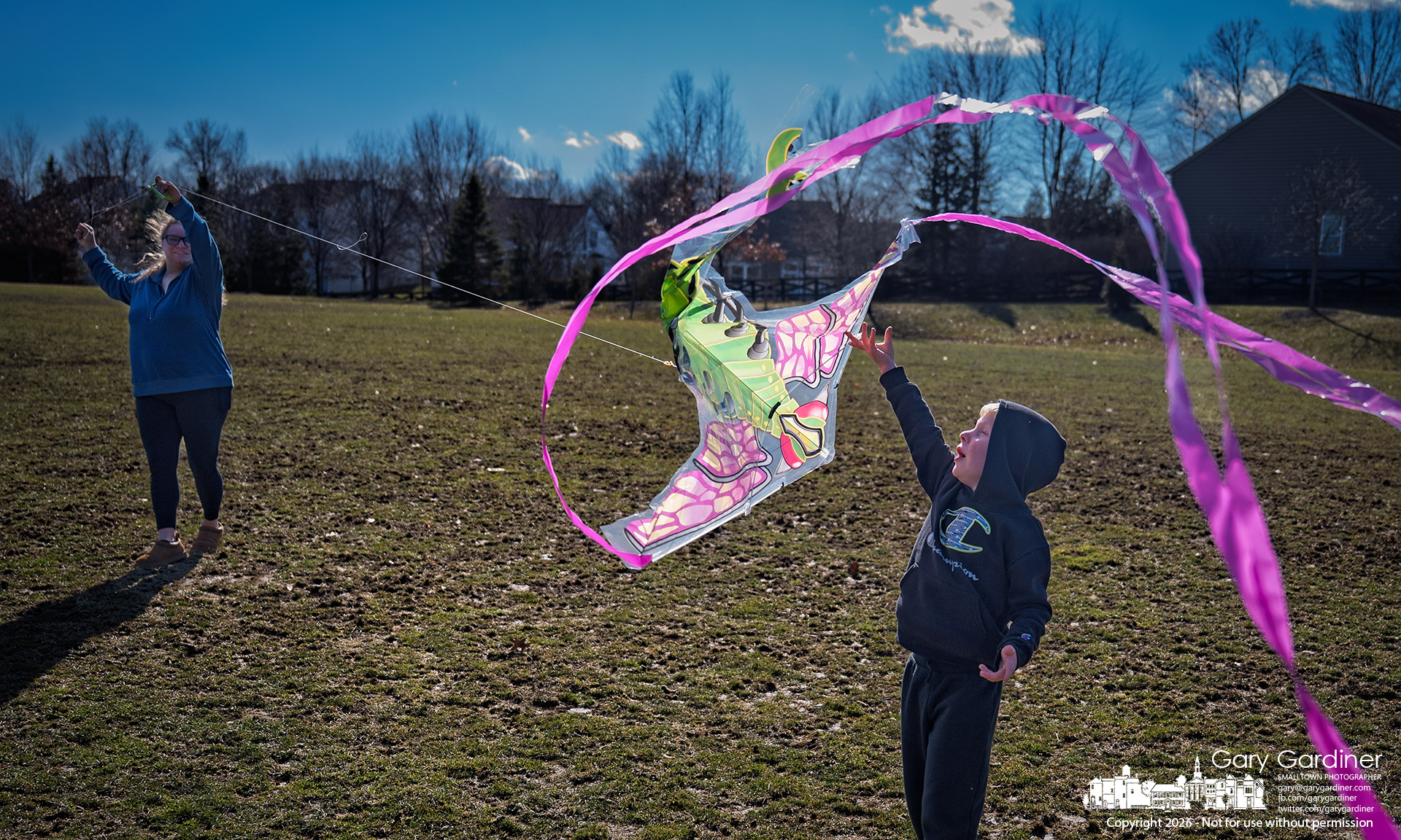 Elliott releases the grasp on his kite as instructed by his mother, who assists him in flying the dragonfly kite on a windy afternoon. (My Final Photo for February 25, 2026)