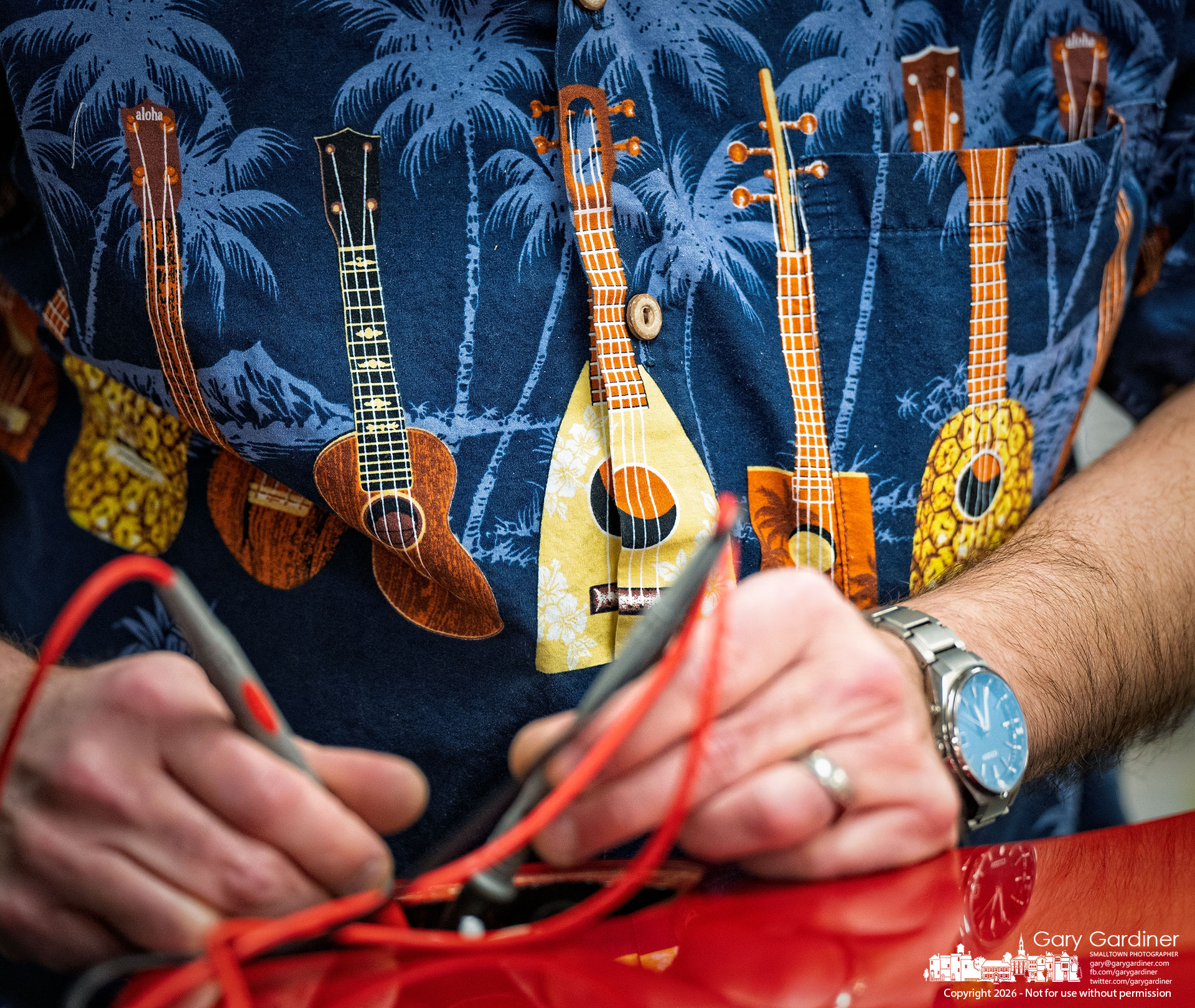 A technician tests the electronics of an electric guitar during a repair at Music & Arts in Uptown Westerville, with a brightly patterned instrument shirt adding an unexpected visual note. (My Final Photo for February 4, 2026)