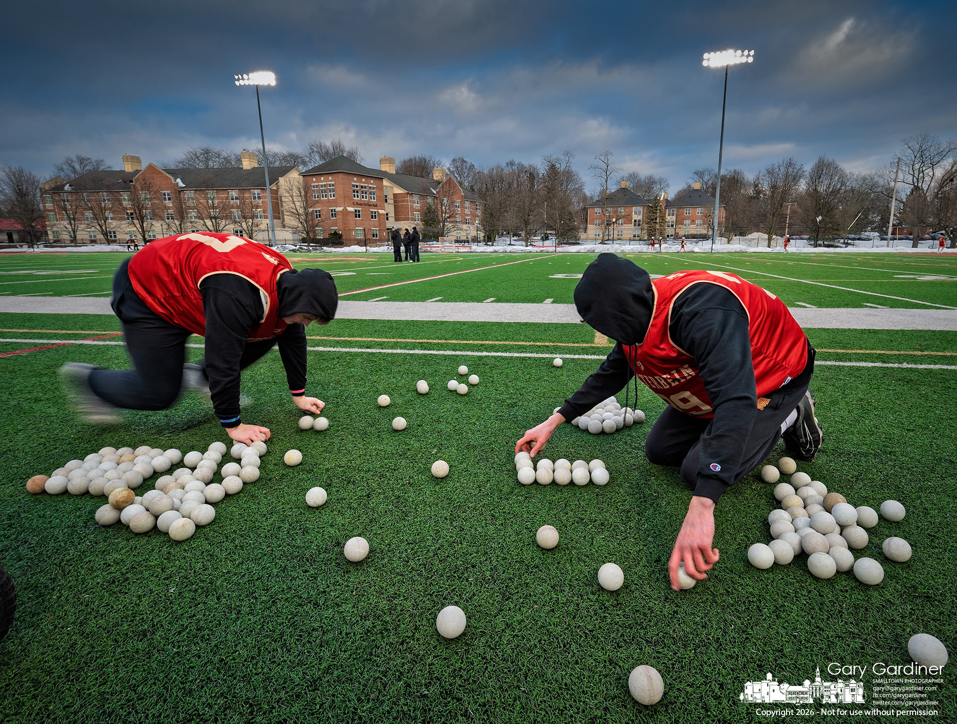 Otterbein lacrosse players count balls after practice, trying to match the number they started with after retrieving errant tosses into the snowbanks surrounding the practice field. (My Final Photo for February 11, 2026)