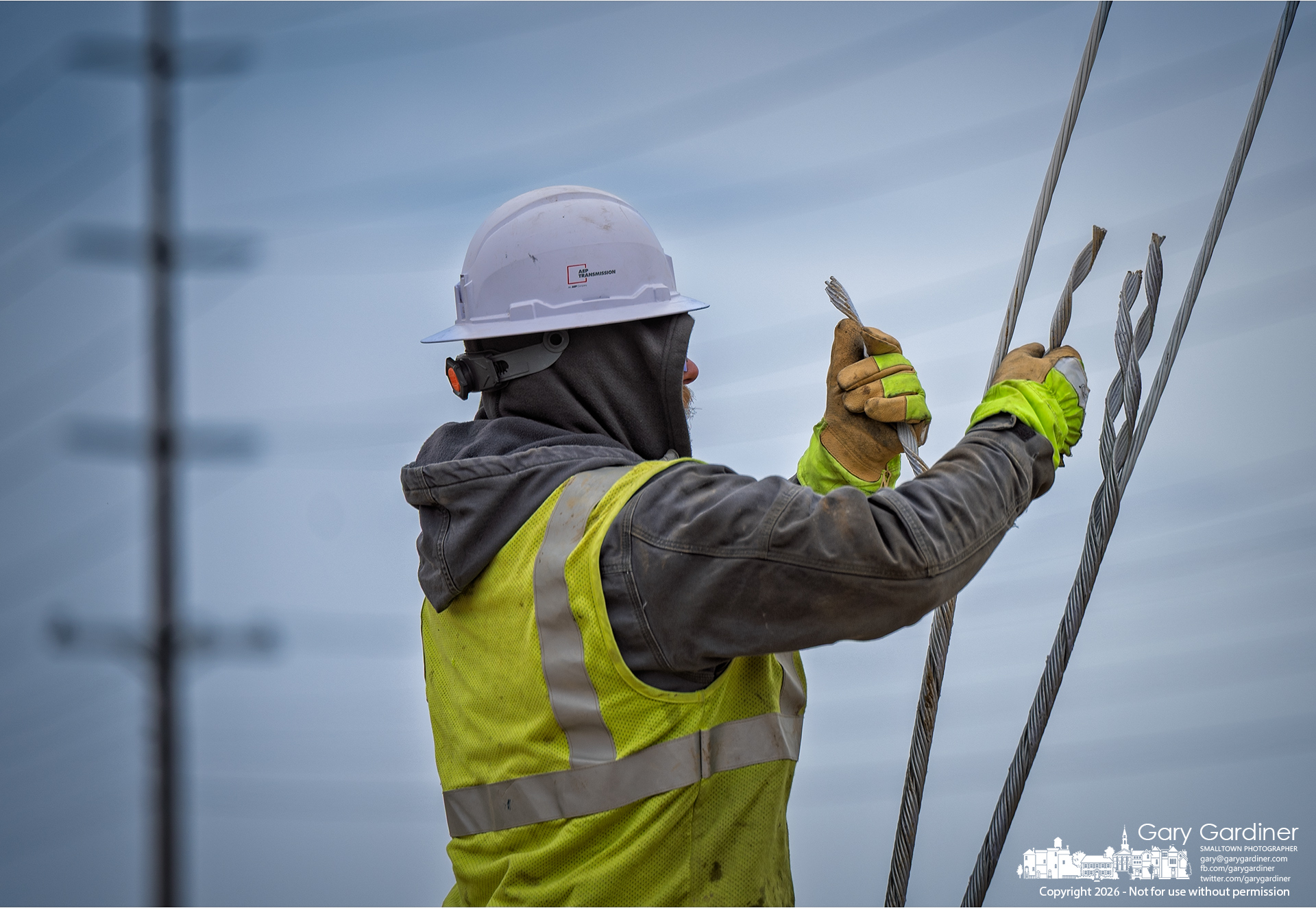 An AEP linesman grips the separated strands of a guy wire during pole-anchoring work on Africa Road. (My Final Photo for March 18, 2026)