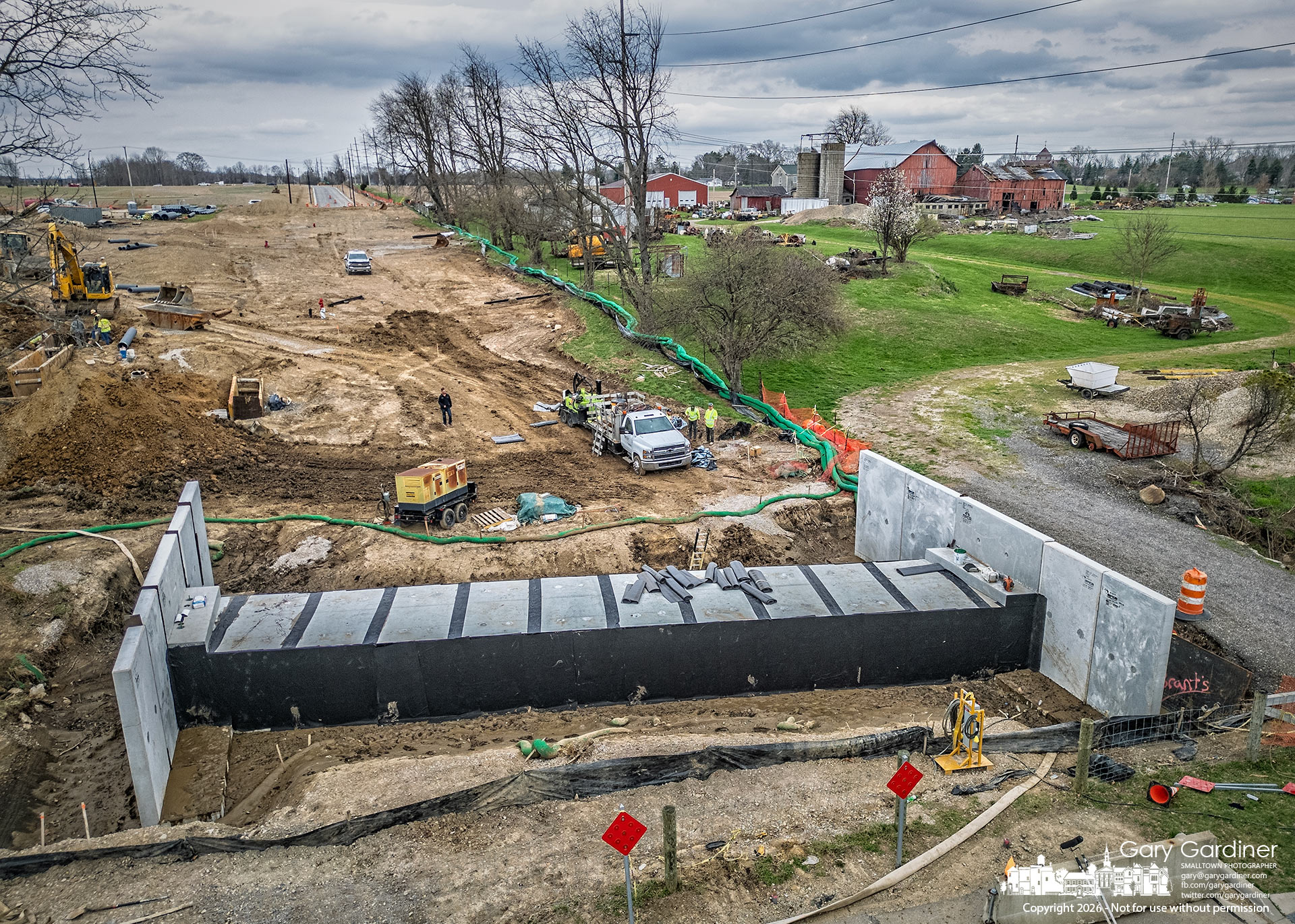 Workers wrap the Westar Bridge culvert in waterproofing materials, hoping to complete the work before rain predicted for the next two days slows their progress. (My Final Photo for March 30, 2026)