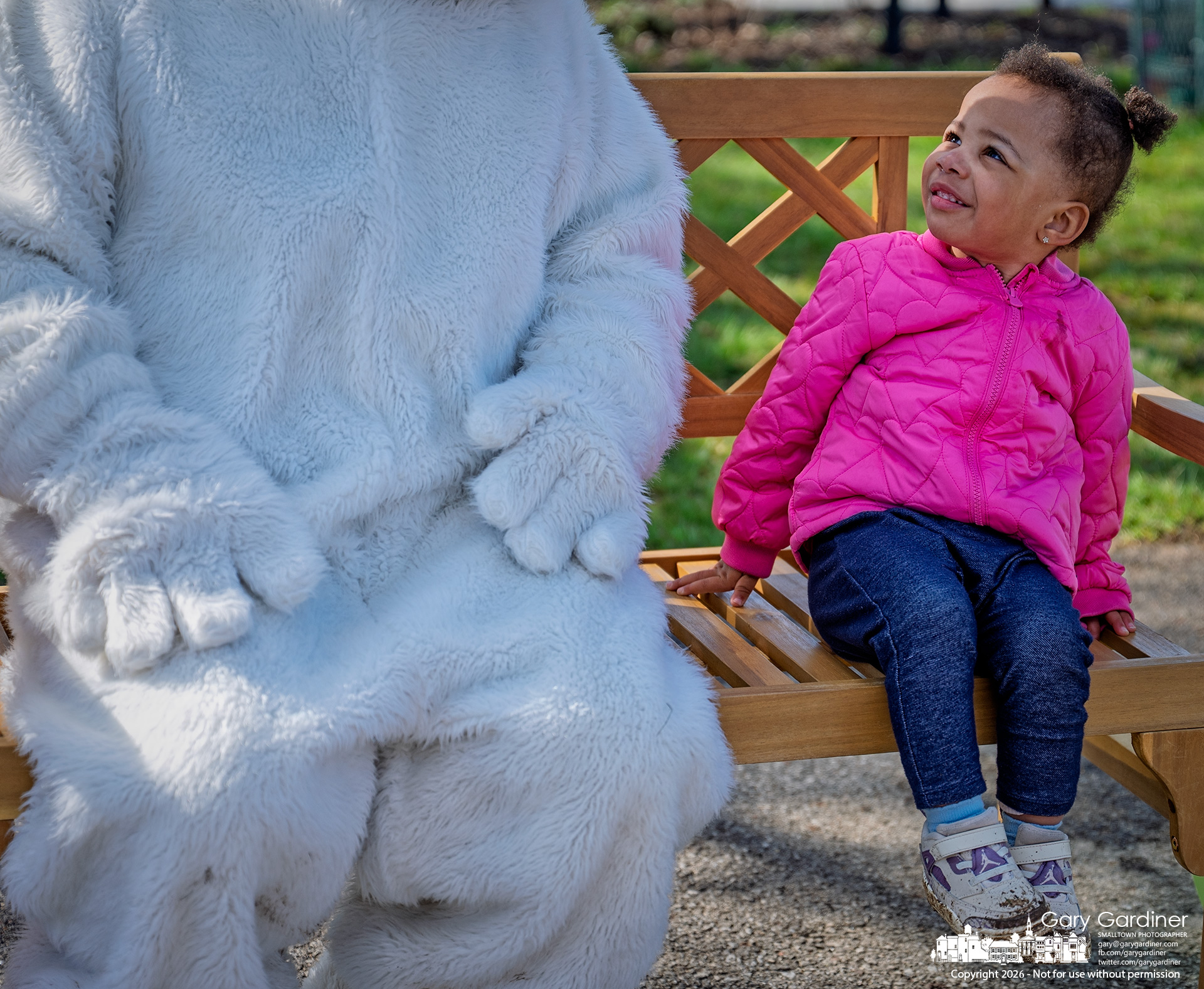 A young girl ponders the oversized rabbit where her parents placed her for a photo at the city's Eggstravaganza egg hunt Saturday. (My Final Photo for March 28, 2026)