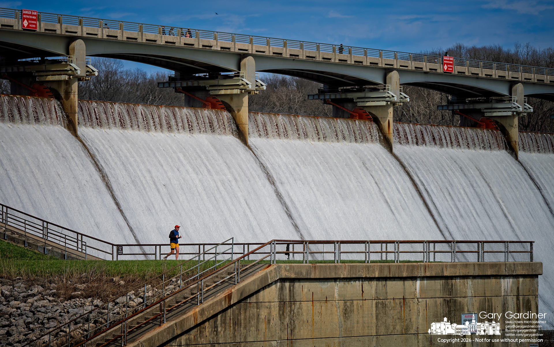 A runner takes advantage of the afternoon sun and spring warmth for a workout at Hoover Dam, where high water from the reservoir runs over the spillway. (My Final Photo for March 29, 2026)
