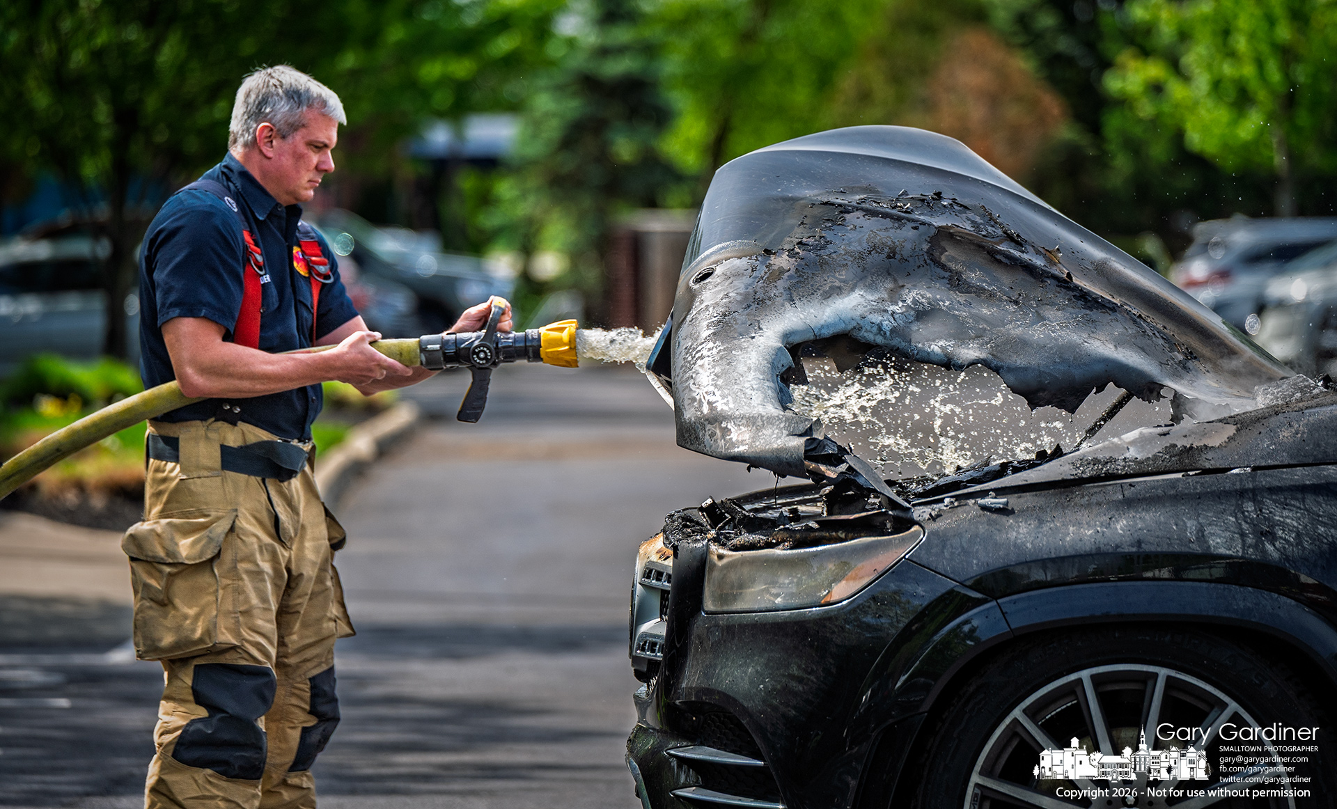 A Westerville firefighter sprays hotspots in the engine compartment of a car that caught fire in a parking lot on North Celveland Ave Monday morning. (My Final Photo for April 27, 2026, by Gary Gardiner)
