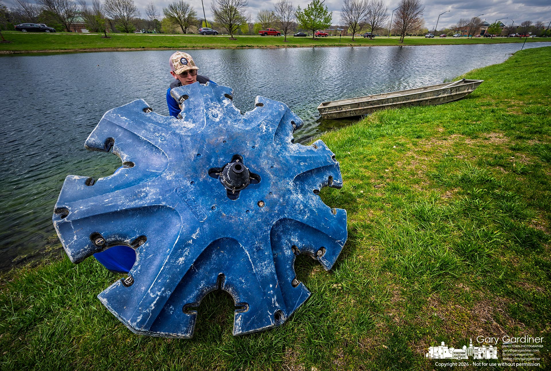 Workers install the five fountains in the pond in front of the community center as warmer weather appears to become the norm. (My Final Photo for April 13, 2026 by Gary Gardiner)