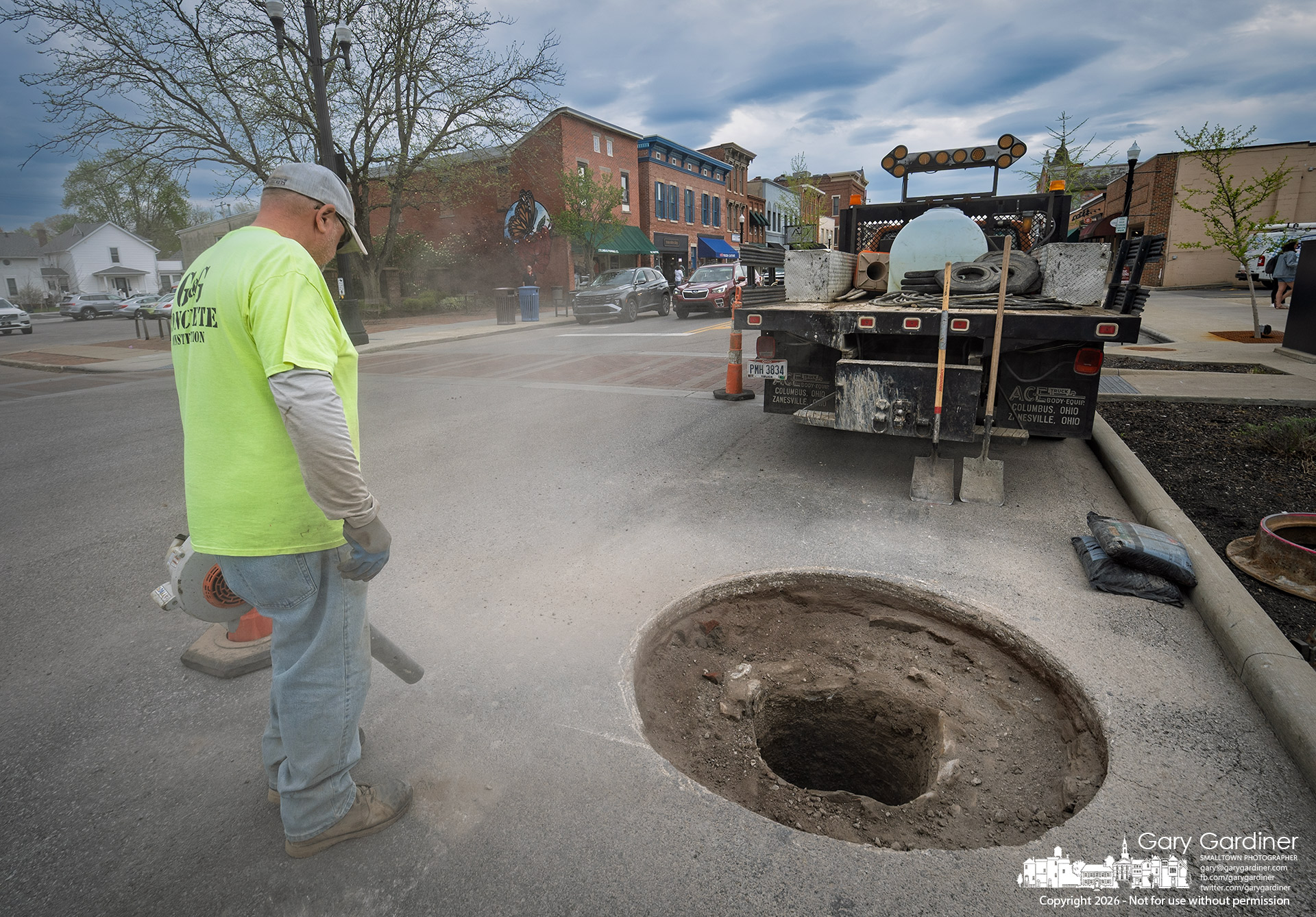 Dirt and dust are cleared from the street after a donut-shaped hole was cut around a manhole cover to make repairs to it at Home and State Streets in Uptown. (My Final Photo for April 10, 2026, by Gary Gardiner)