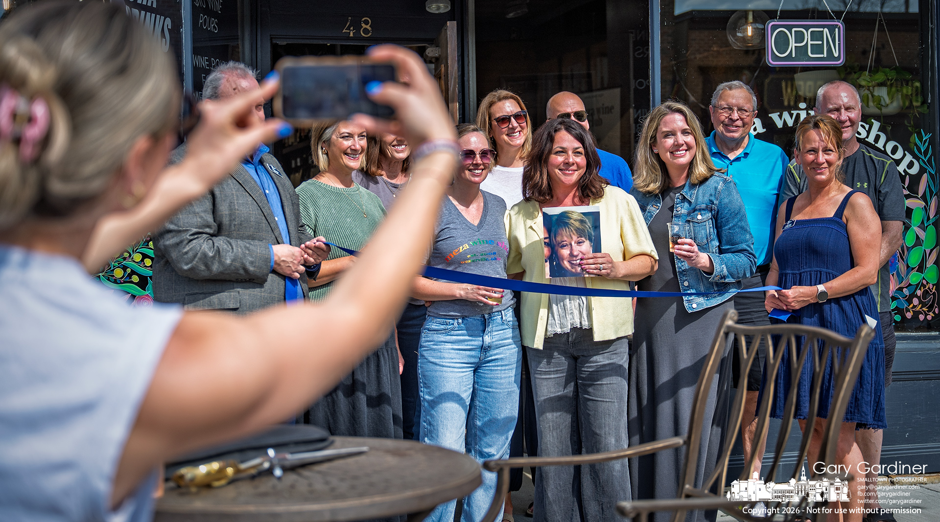Tatjana Brown, with family, friends, and staff, poses before the 18th anniversary ribbon cutting for Meza, her wine shop in Uptown Westerville. (My Final Photo for April 17, 2026 by Gary Gardiner)