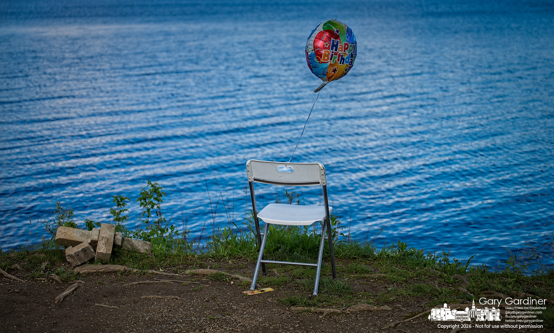 An empty chair with a “Happy Birthday” balloon sits near the shoreline at Red Bank Park, placed there by two men who marked their late father’s birthday with a fishing trip at Hoover Reservoir, where they often fished with him as children. (My Final Photo for April 30, 2026, by Gary Gardiner)