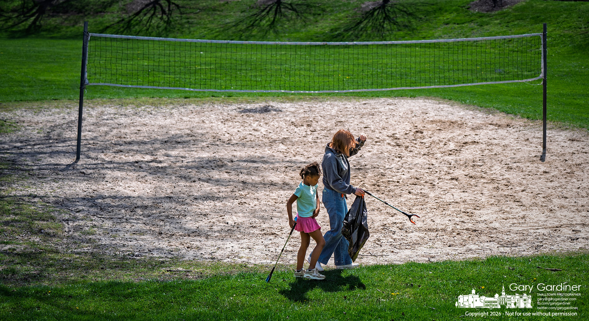 Mother and daughter search for debris in the grass around the volleyball court at Alum Creek Park North during Sustainable Westerville Kids Clean-Up Day. (My Final Photo for April 12, 2026, Photo by Gary Gardiner)