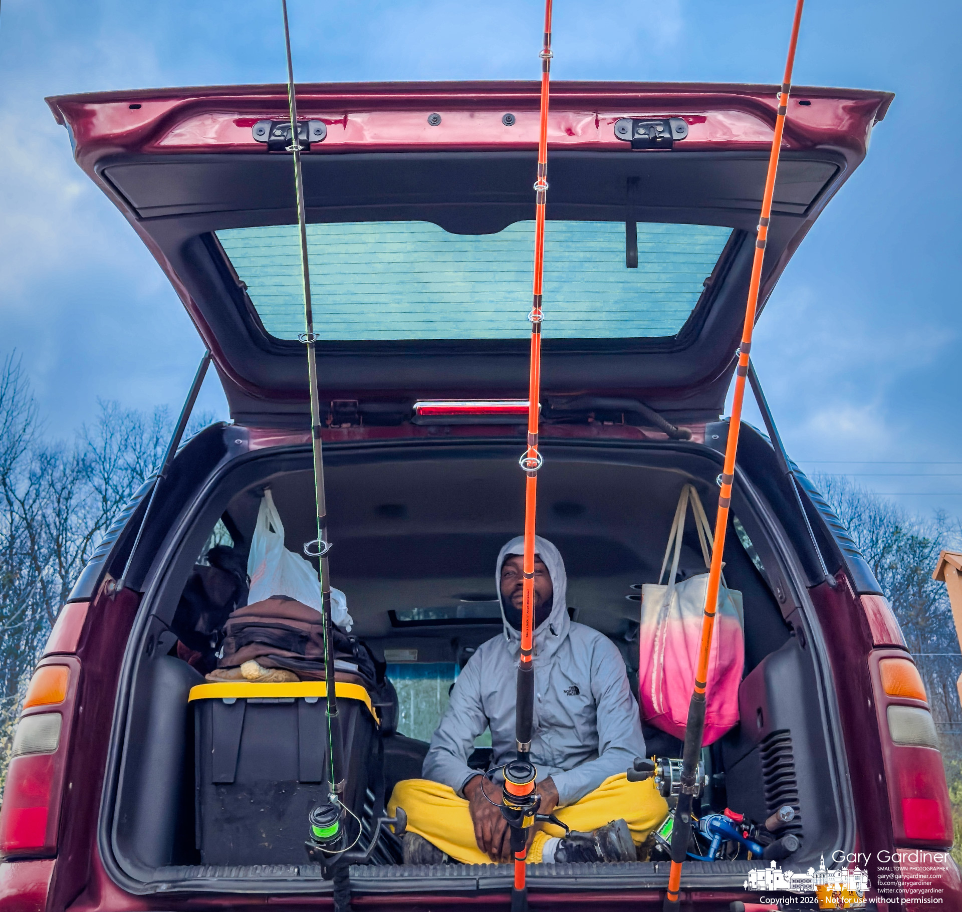 A fisherman sits in the open hatch of his SUV at Hoover Reservoir’s Twin Bridges after casting his rods into the water, taking shelter from the wind and cold. (My Final Photo for April 5, 2026)