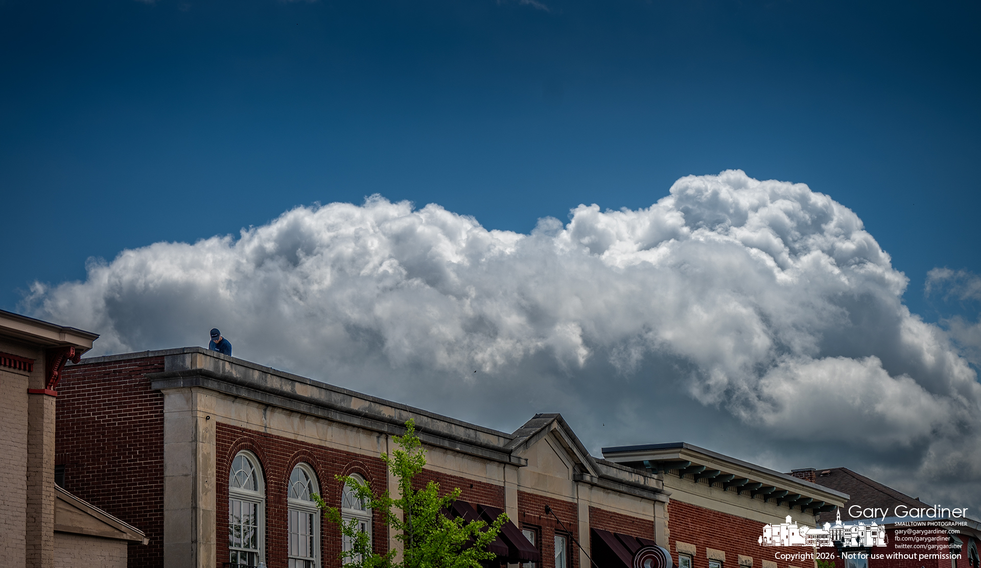 A power washer cleans the roof above Asterisk in Uptown as scattered clouds cast shifting shadows across the city. (My Final Photo for April 28, 2026, by Gary Gardiner )