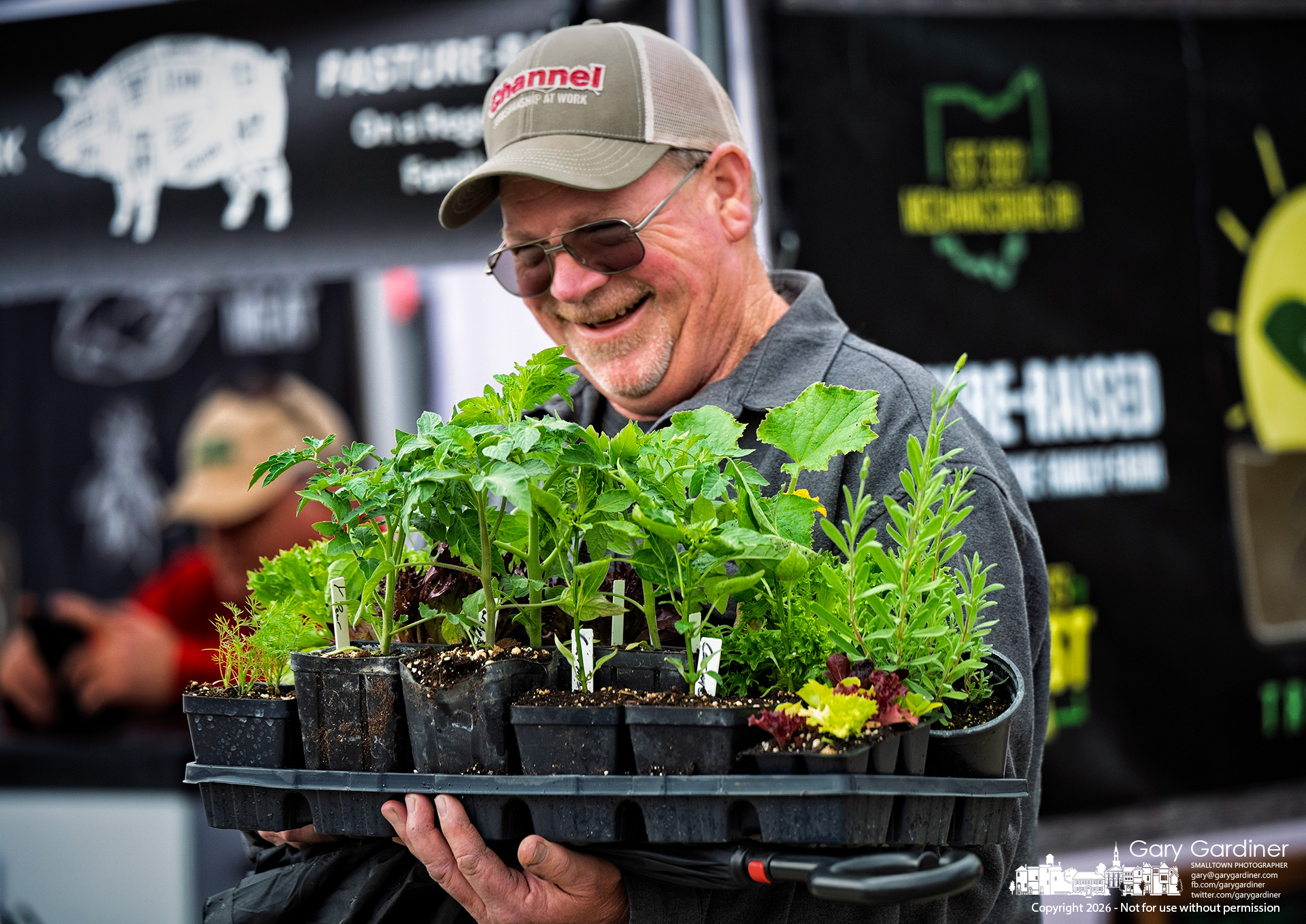 A gardener smiles as he is discovered with a tray of vegetable and herb plants intended for his home garden on the opening day of the Saturday Farmers market in Westerville. (My Final Photo for May 16. Photo by Gary Gardiner)