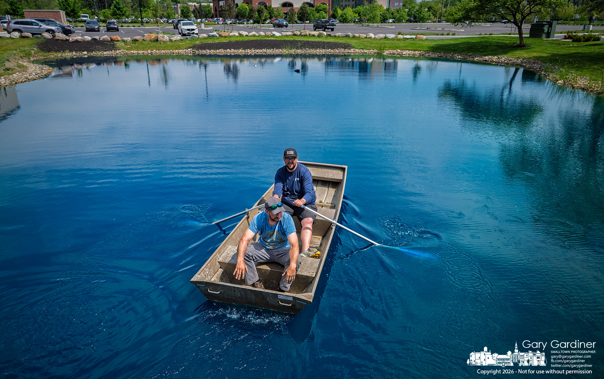 A water treatment crew paddles across the pond behind Smash Park and Middlefield Bank to retrieve their equipment after treating the water with copper sulfate to reduce algae in the small lake. ()My Final Photo for May 12, 2026. Photo by Gary Gardiner)