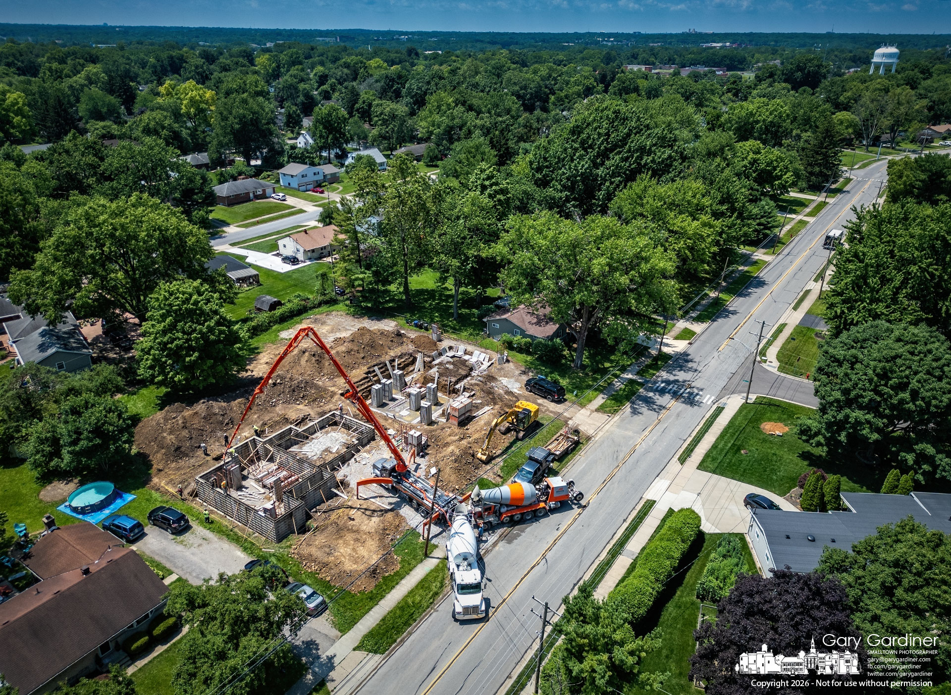 A pump truck loads concrete into metal forms to build the outer walls of a house under construction on East Walnut. (My Final Photo for June 29, 2026. Photo by Gary Gardiner)