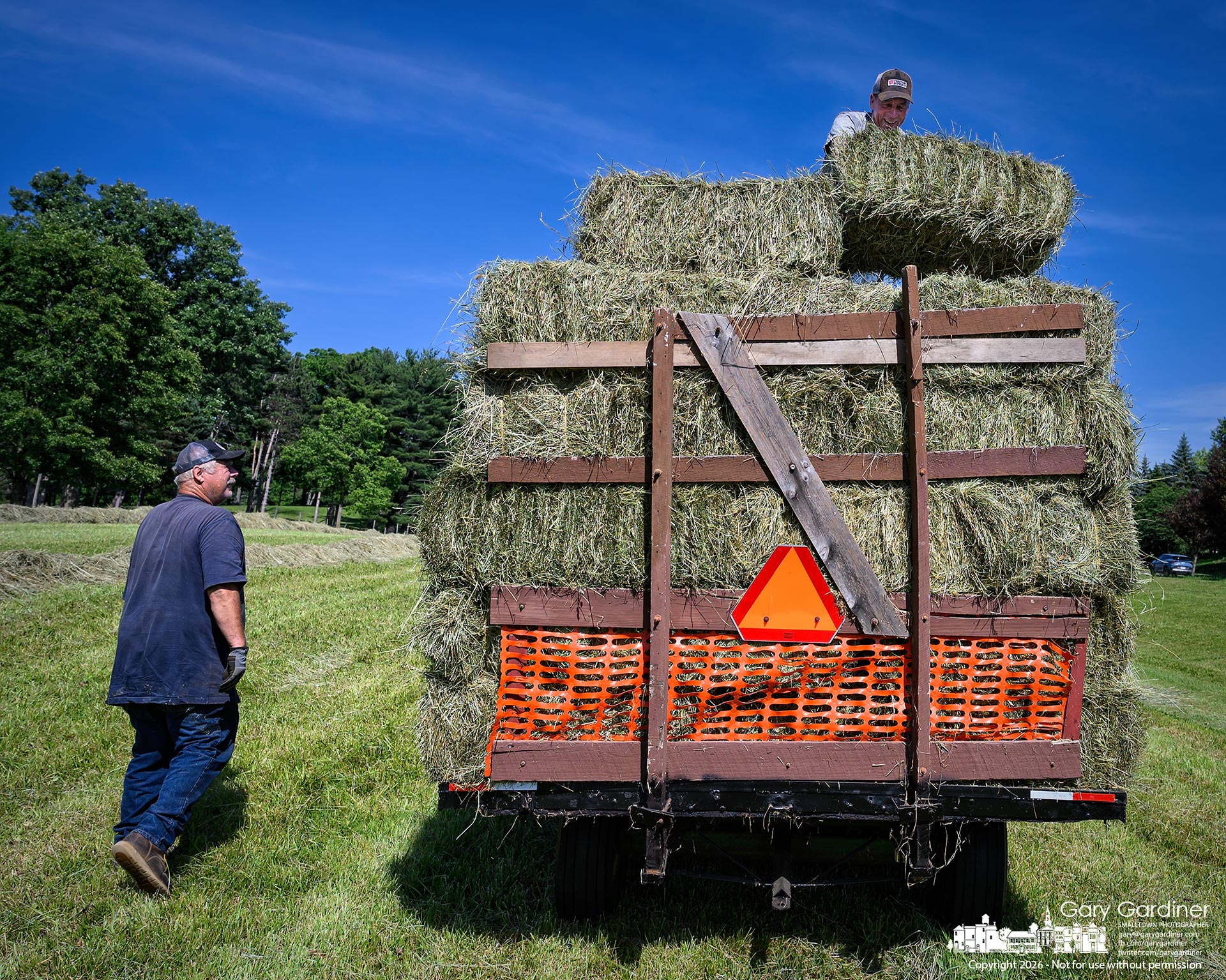 Kevin Scott, after finishing baling his hay at the Braun Farm, helps Duane Yarnell load his wagons in the field at his farm on Africa Road. (My Final Photo for June 4, 2026. Photo by Gary Gardiner)