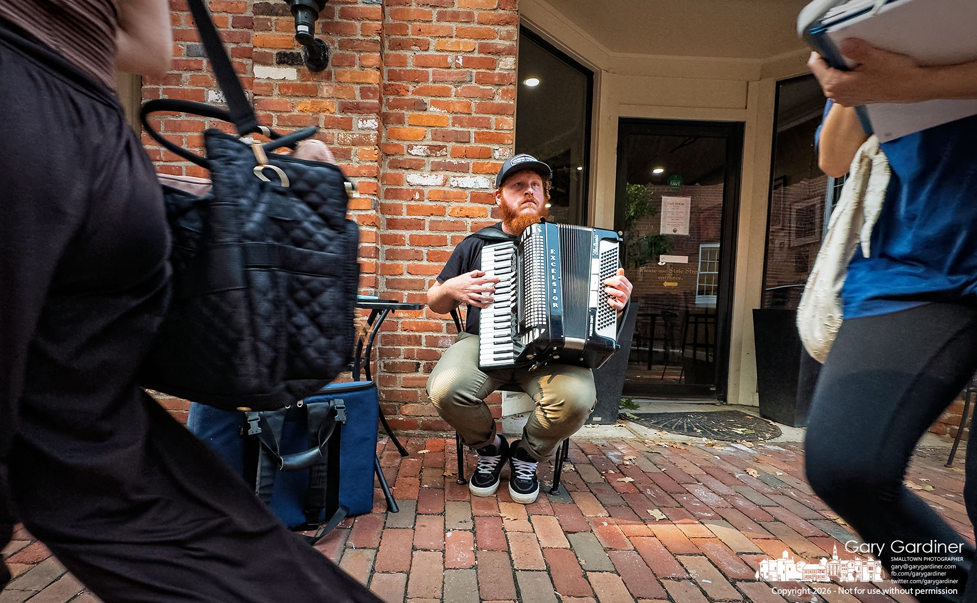 Accordion busker Spencer Ripley practices on the brickwalk before beginning his evening of performances in front of Java Central. (My Final Photo for July 28, 2026. Photo by Gary Gardiner)