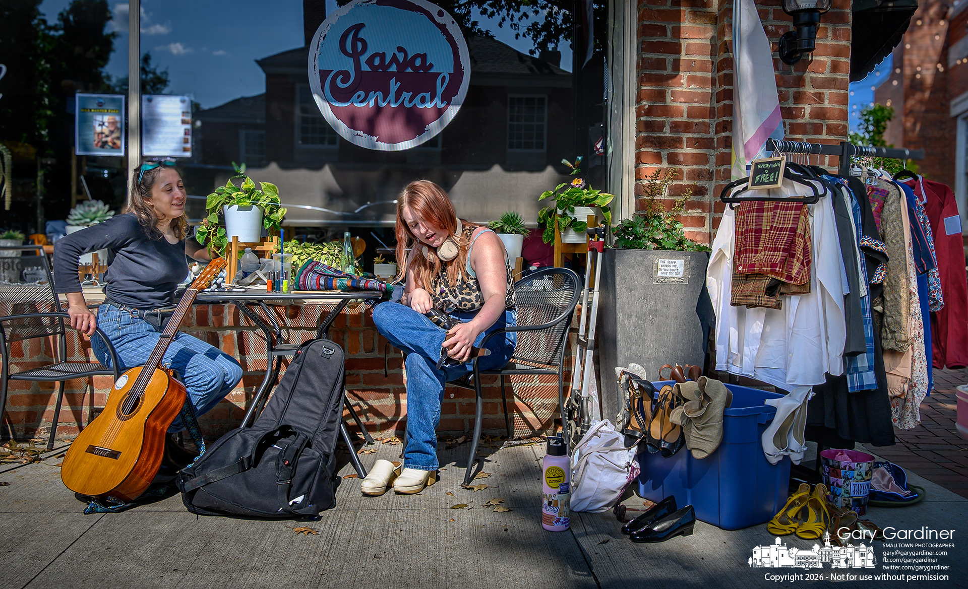 A woman tries on a pair of shoes offered for free from a collection in front of Java Central on South State. (My Final Photo for July 29, 2026. Photo by Gary Gardiner)