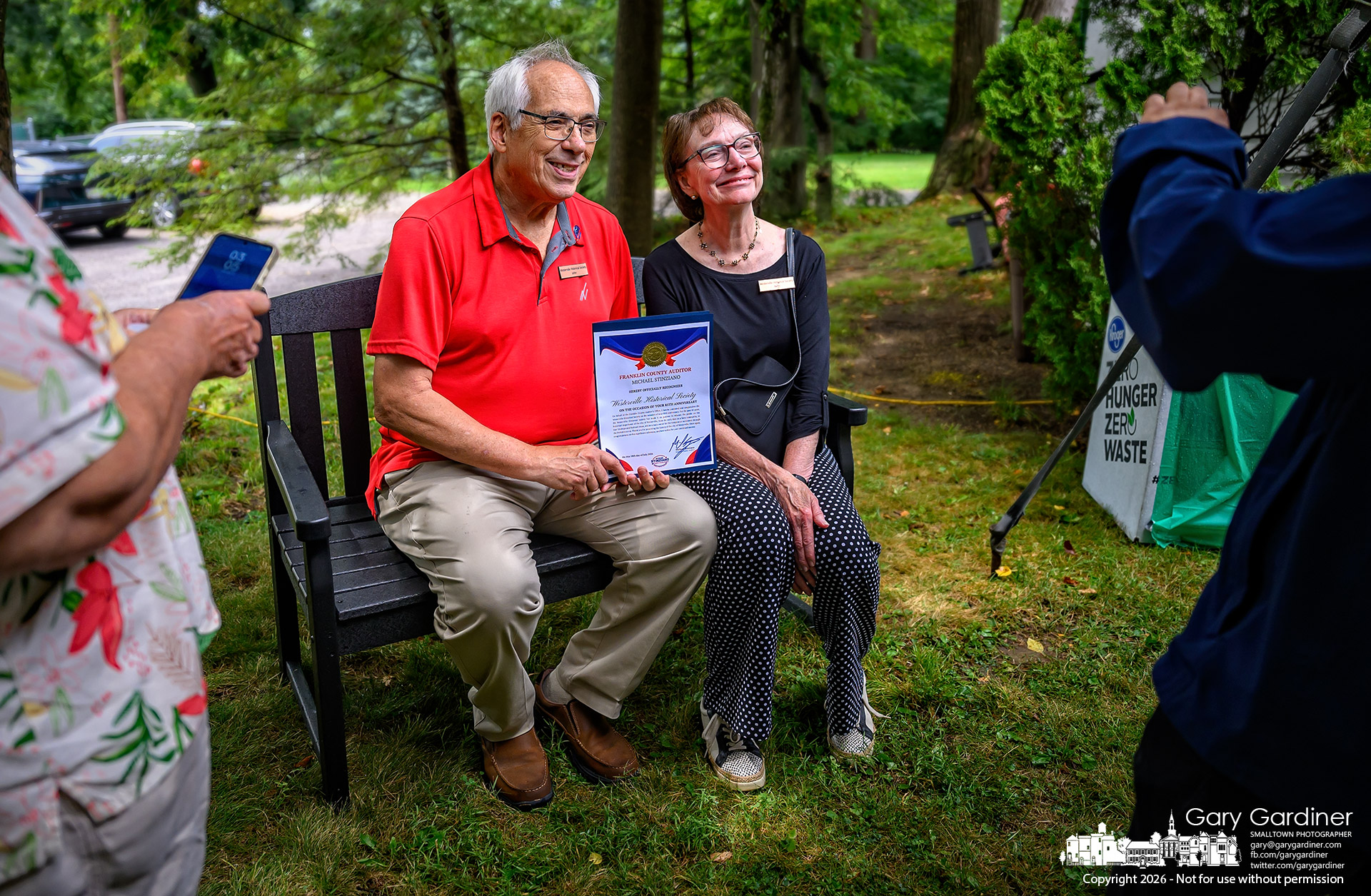 John Bokros and Beth Weinhardt pose with the State Auditor's proclamation honoring the Westerville Historical Society's 85th anniversary at a celebration at the Hanby House on West Main Street, where the society was given a new park bench by the Westerville Lions Club.