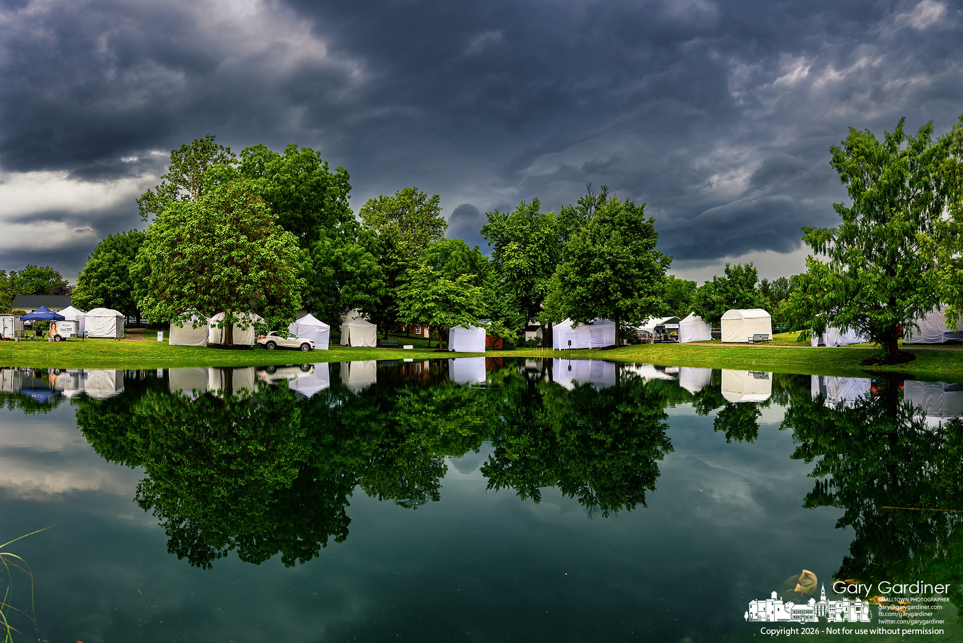 Storm clouds darken the sky as artists and vendors set up in Heritage Park for Saturday's Music and Arts Festival. (My Final Photo for July 10. Photo by Gary Gardiner)