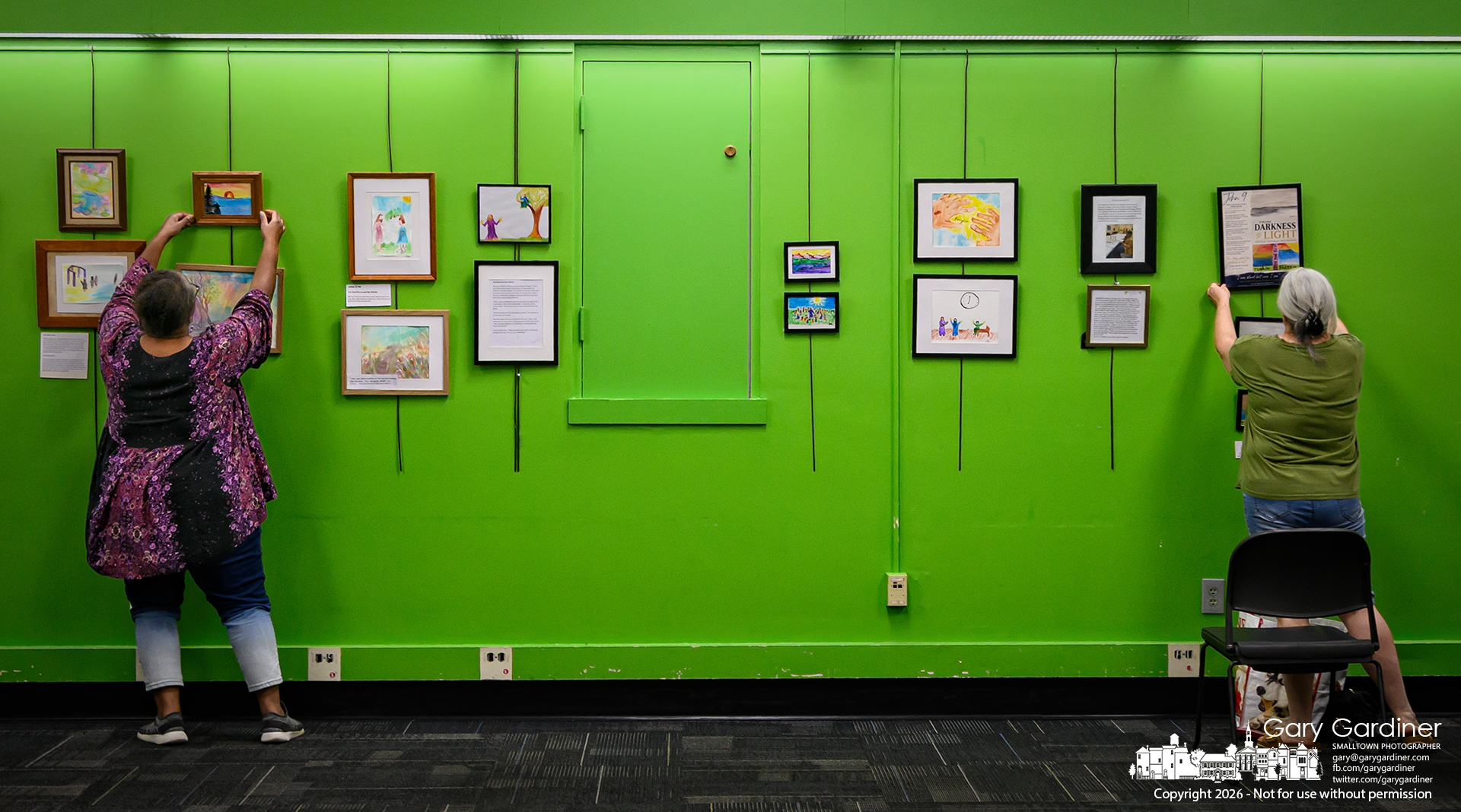 Artists arrange their work on the walls of the library meeting rooms. (My Final Photo for August 7, 2026. Photo by Gary Gardiner)