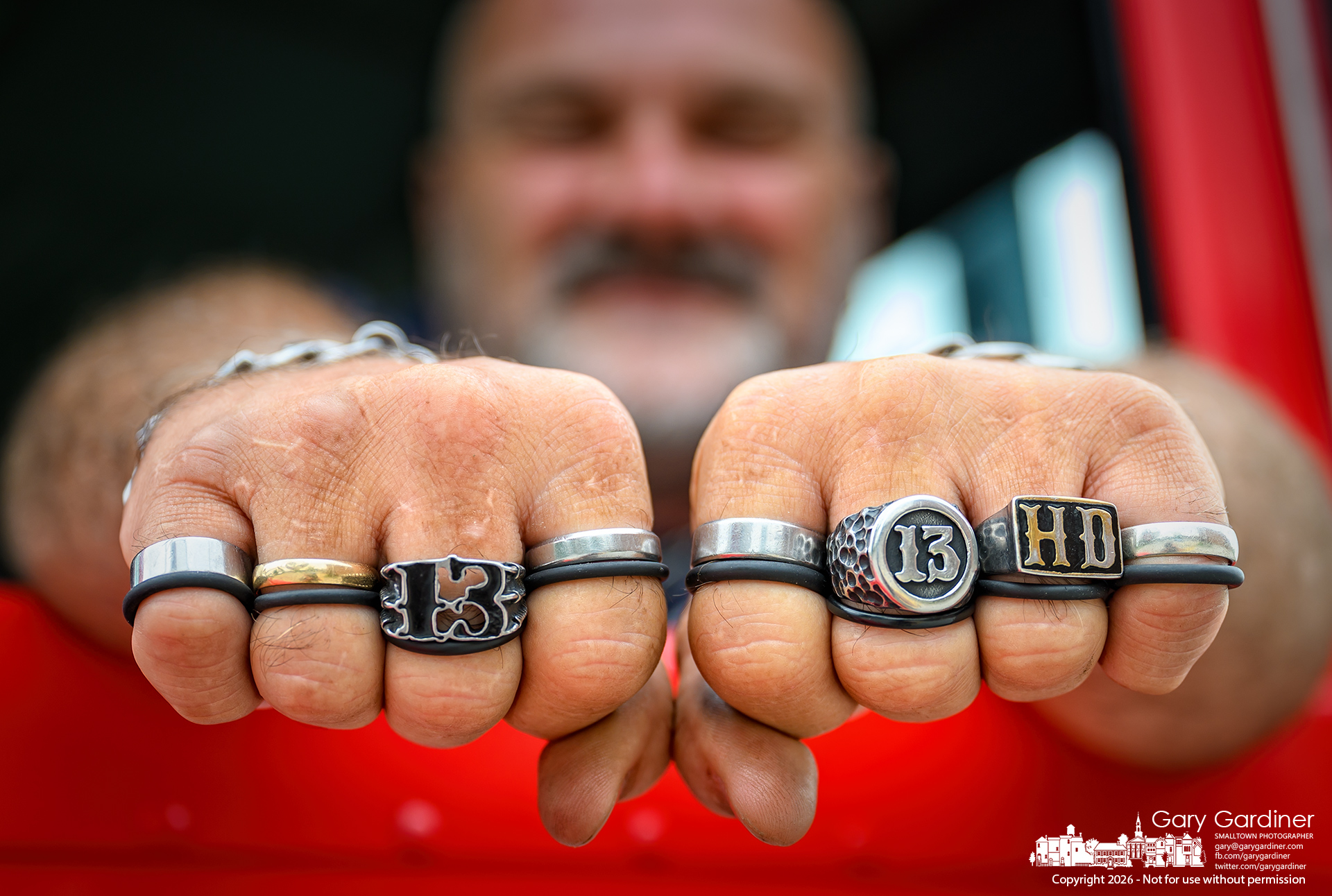 Rusty McQuirt shows the eight rings he wears, each signifying a Harley-Davidson motorcycle he owns. (My Final Photo for August 1, 2026. Photo by Gary Gardiner)