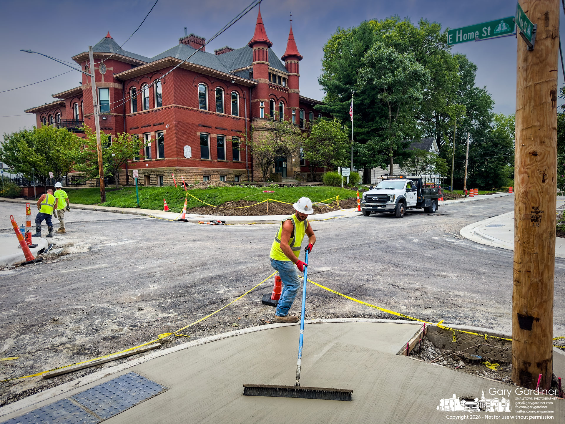 Contractors struggle after recent heavy rainstorms to pour the sidewalks on Vine Street in front of Emerson Elementary in time for school, which begins in a week. (My Final Photo for August 12, 2026. Photo by Gary Gardiner)