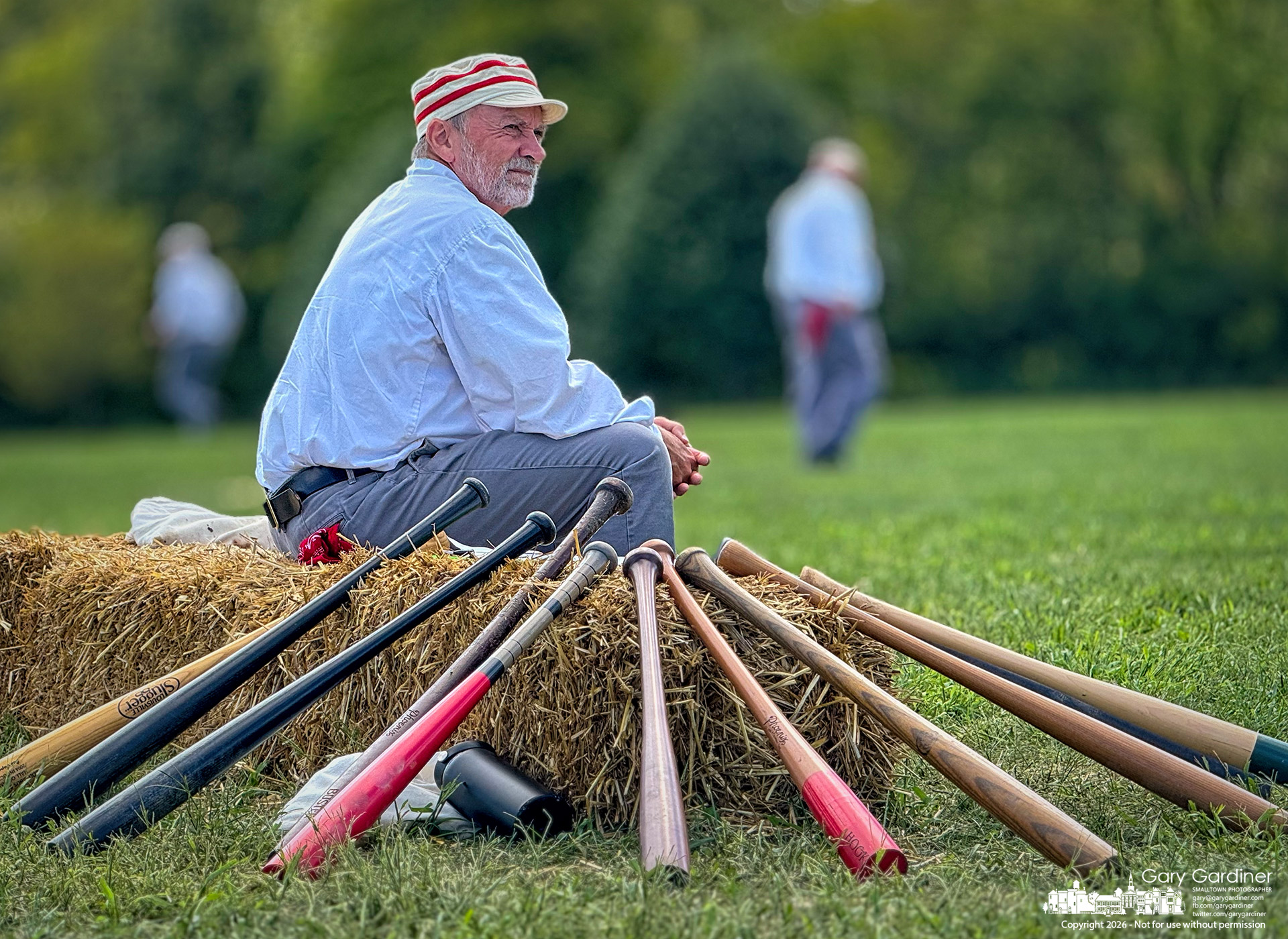 A base ball player dressed in a vintage uniform watches from the hay bale bench during play Sunday afternoon in Westerville. (My Final Photo for September 6, 2026. Photo by Gary Gardiner)