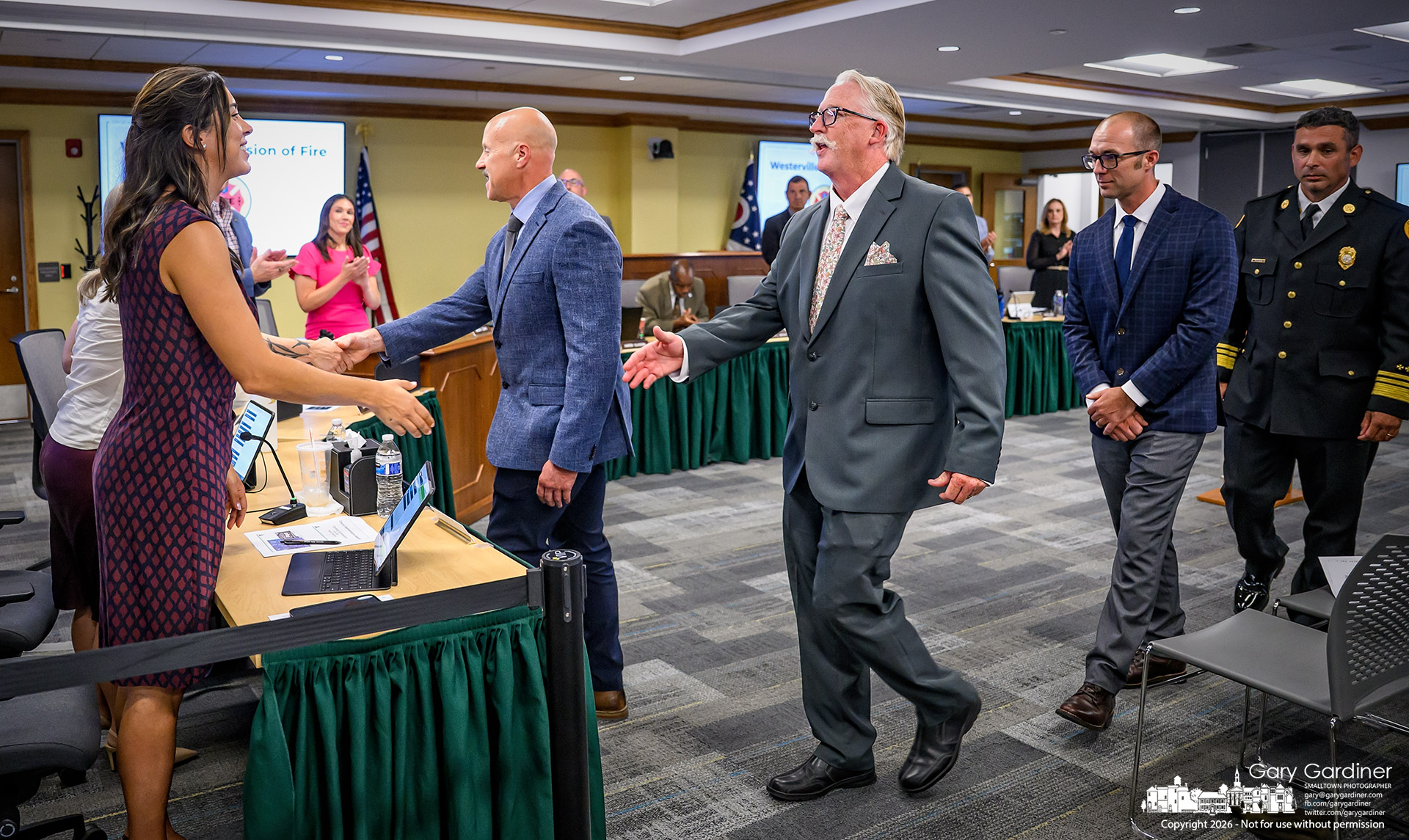 Westerville Councilwoman Daniela Beckett receives newly sworn-in fire chiefs after their introduction to the council Tuesday night. From left, in a blue-gray coat, are Deputy Chief Ralph Casto, overseeing the Fire Prevention Bureau and community risk reduction; Dan Lundy, Deputy Fire Chief of Operations; and Deputy Fire Chief for EMS, Wes Lewis. On the right is Fire Chief Josh Lester. (My Final Photo for September 1, 2026. Photo by Gary Gardiner)