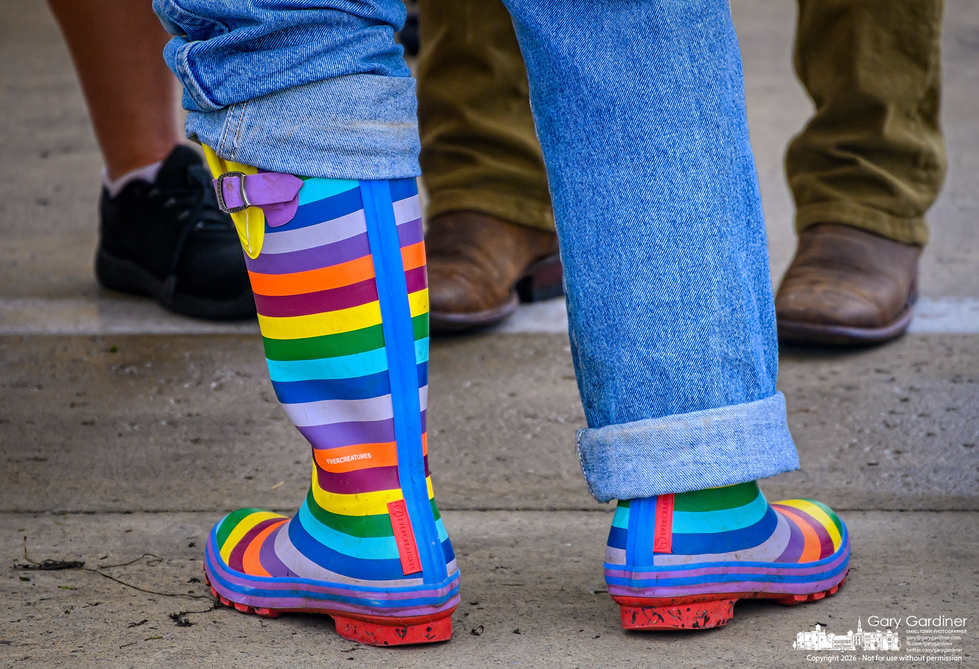 A New Albany Organics farmer’s colorful mud boots get an unexpected showing when a jeans leg catches on one boot as she tends her stand at the Saturday Farmers Market. (My Final Photo for September 5, 2026. Photo by Gary Gardiner)
