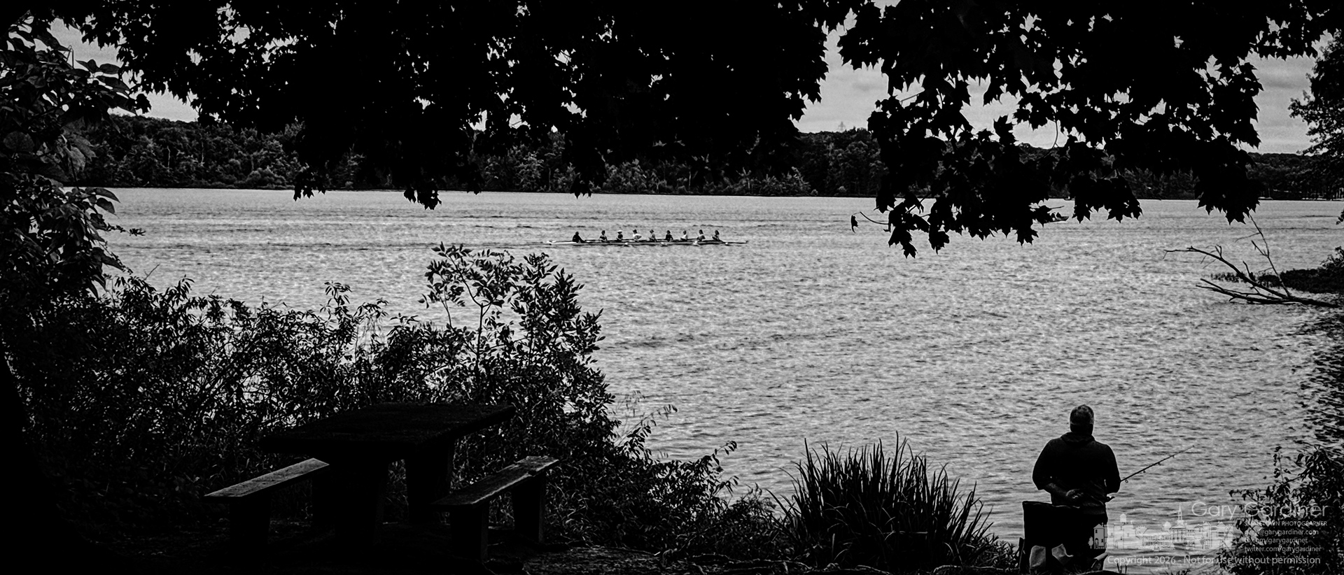 One of the Westerville Crew boats makes practice runs past Red Bank Park on Hoover, where several anglers try their luck in the high waters. (My Final Photo for September 23, 2026. Photo by Gary Gardiner)