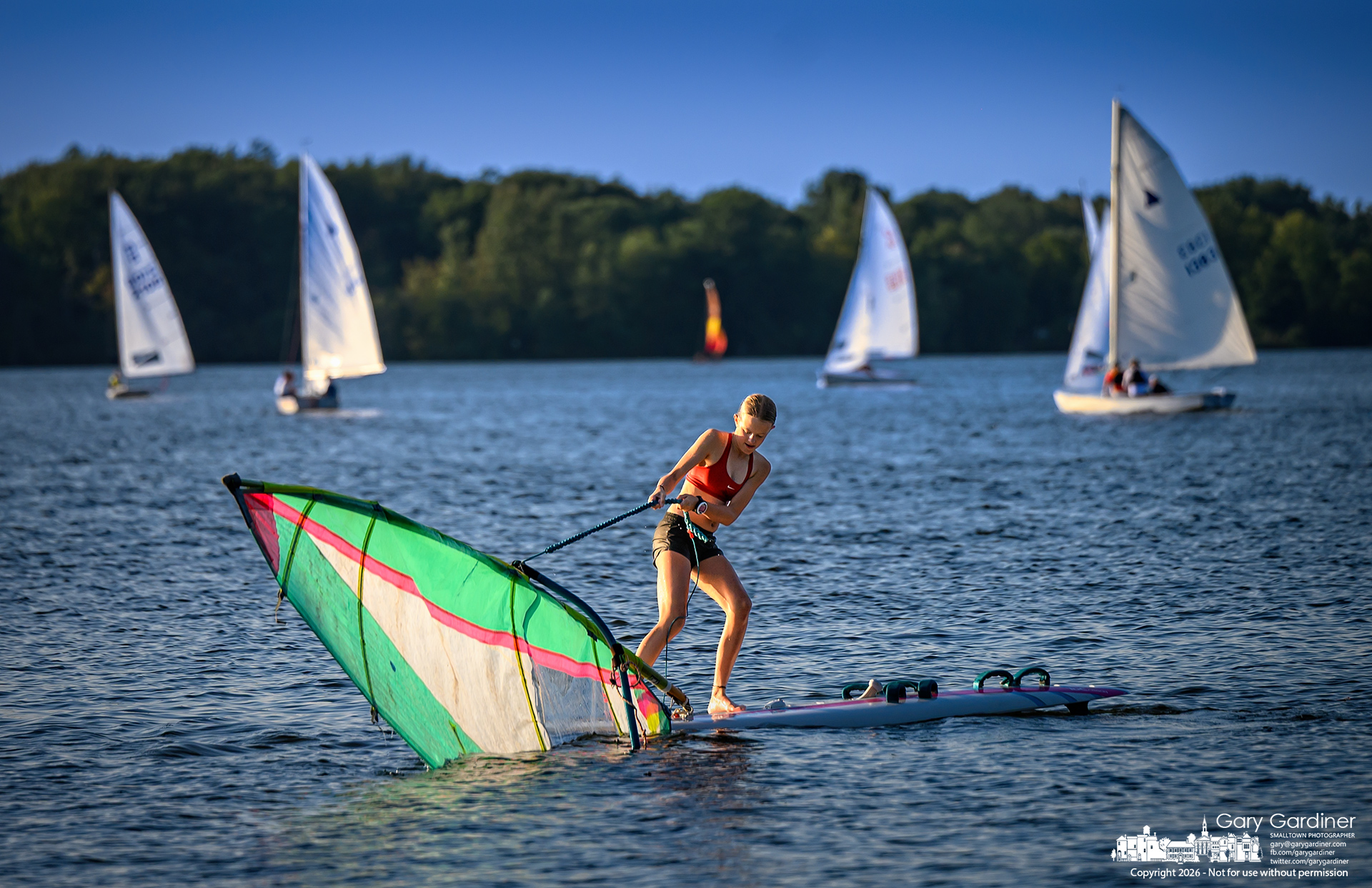 A sailboarder struggles to pull her sail out of the water on the last Wednesday race day of the season at Hoover Sail Club. (My Final Photo for September 2, 2026. Photo by Gary Gardiner)