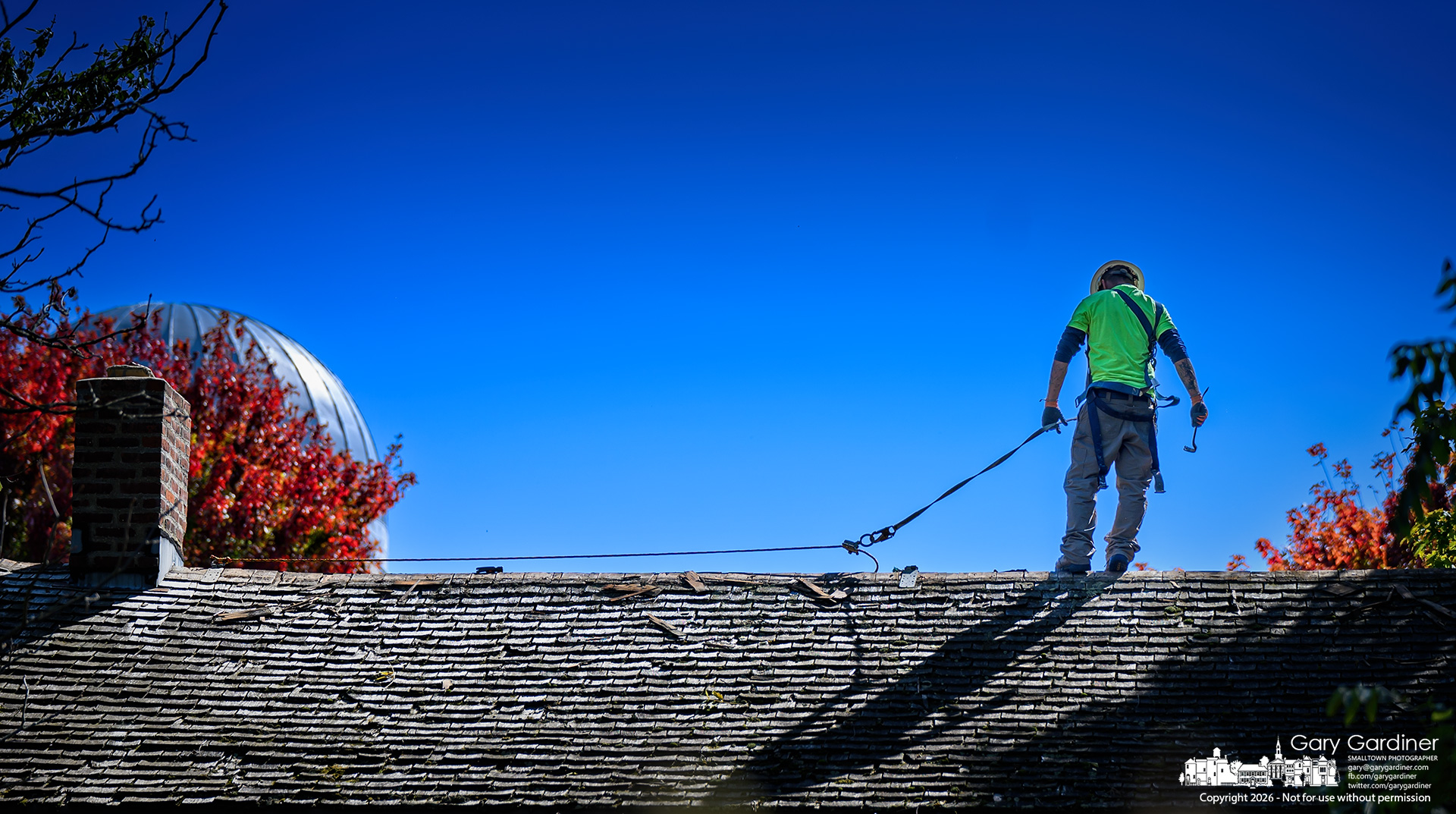 A roofer steadies himself on the peak of the Hanby House where the old cedar shake shingles are being removed and replaced with new ones.(My Final Photo for October 7, 2026. Photo by Gary Gardiner)