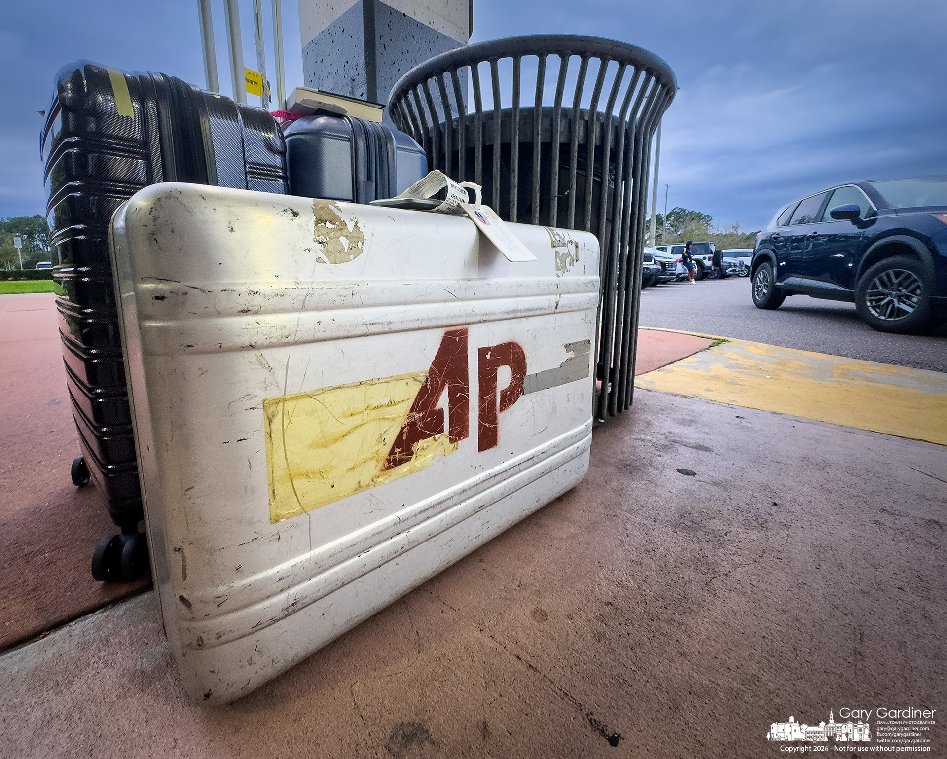 A well-used but still sturdy Associated Press Halliburton travel case sits outside a Florida airport, waiting for the owner's driver to bring the vacation vehicle around. (My Final Photo for October 18, 2026. Photo by Gary Gardiner)