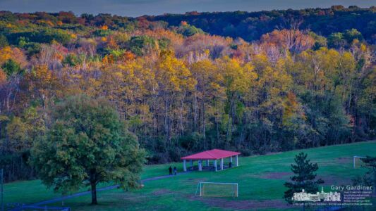 A couple walks across the field below Hoover Dam as the setting sun brightens the fall colors in the tops of trees. My Final Photo for Oct. 26, 2017. A couple walks across the field below Hoover Dam as the setting sun brightens the fall colors in the tops of trees. My Final Photo for Oct. 26, 2017.