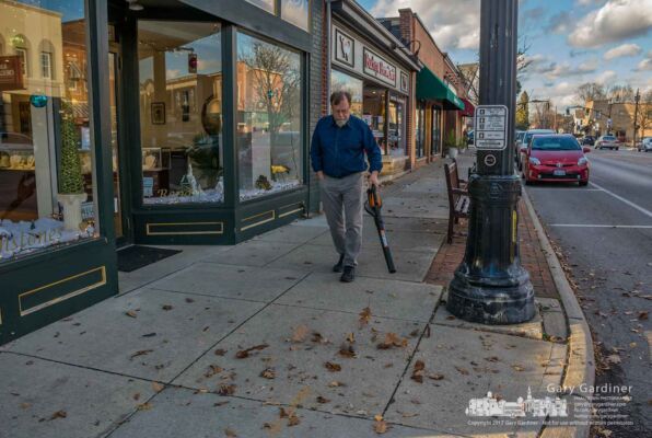Jeweler Bill Morgan uses a battery-powered blower to clear leaves from inside and in front of his store in Uptown in what he says is continuing battle as the wind whips around the corner of his State and Main building. My Final Photo for Dec. 6, 2017. Jeweler Bill Morgan uses a battery-powered blower to clear leaves from inside and in front of his store in Uptown in what he says is continuing battle as the wind whips around the corner of his State and Main building. My Final Photo for Dec. 6, 2017.